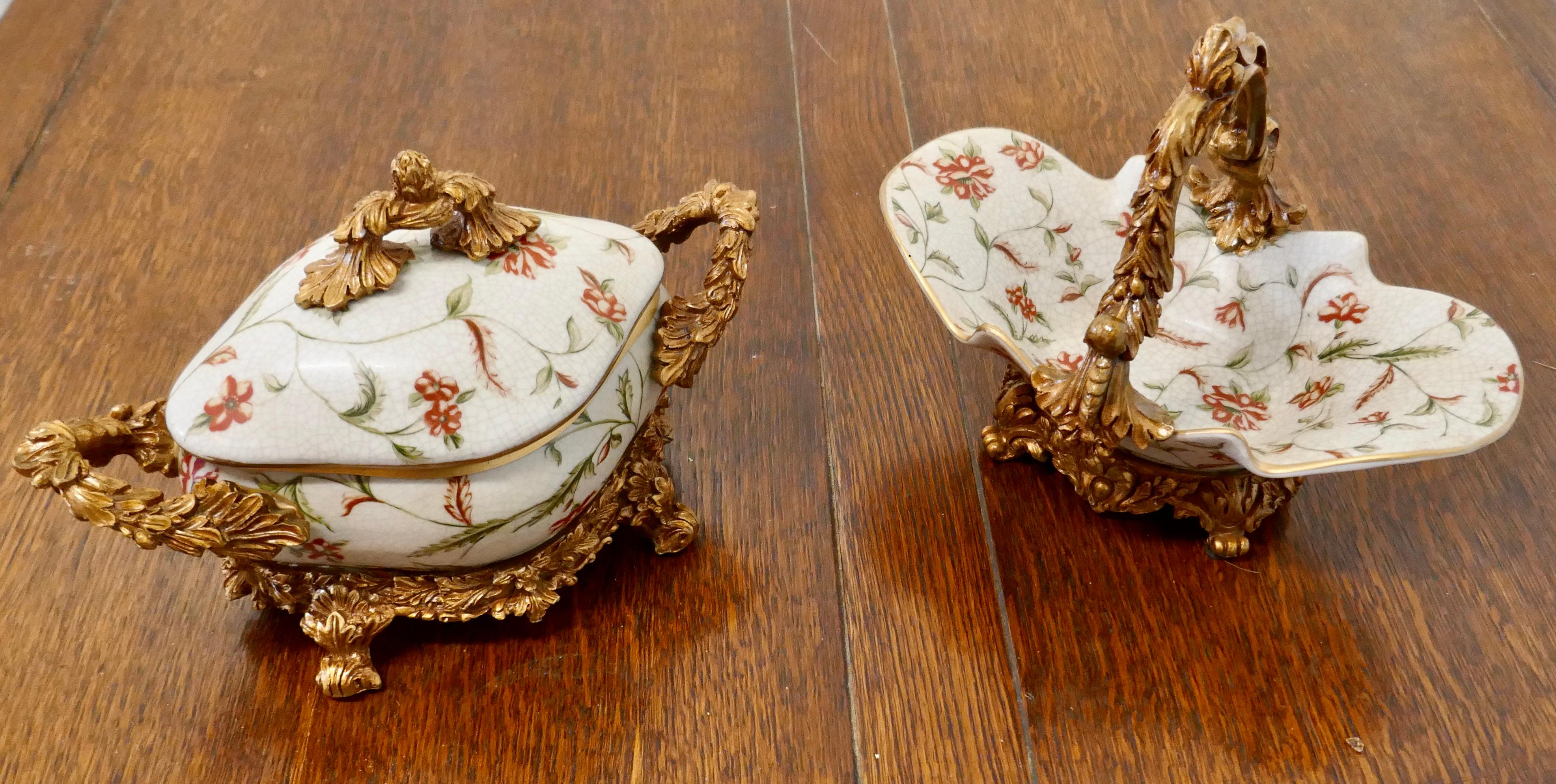 Pair of French Rococo style sweet Dishes

A very attractive pair of sweet dishes one with a handle, the other with a lid the dishes have a slightly crazed finish with simulated ormolu stands and handles, both dishes are in very good