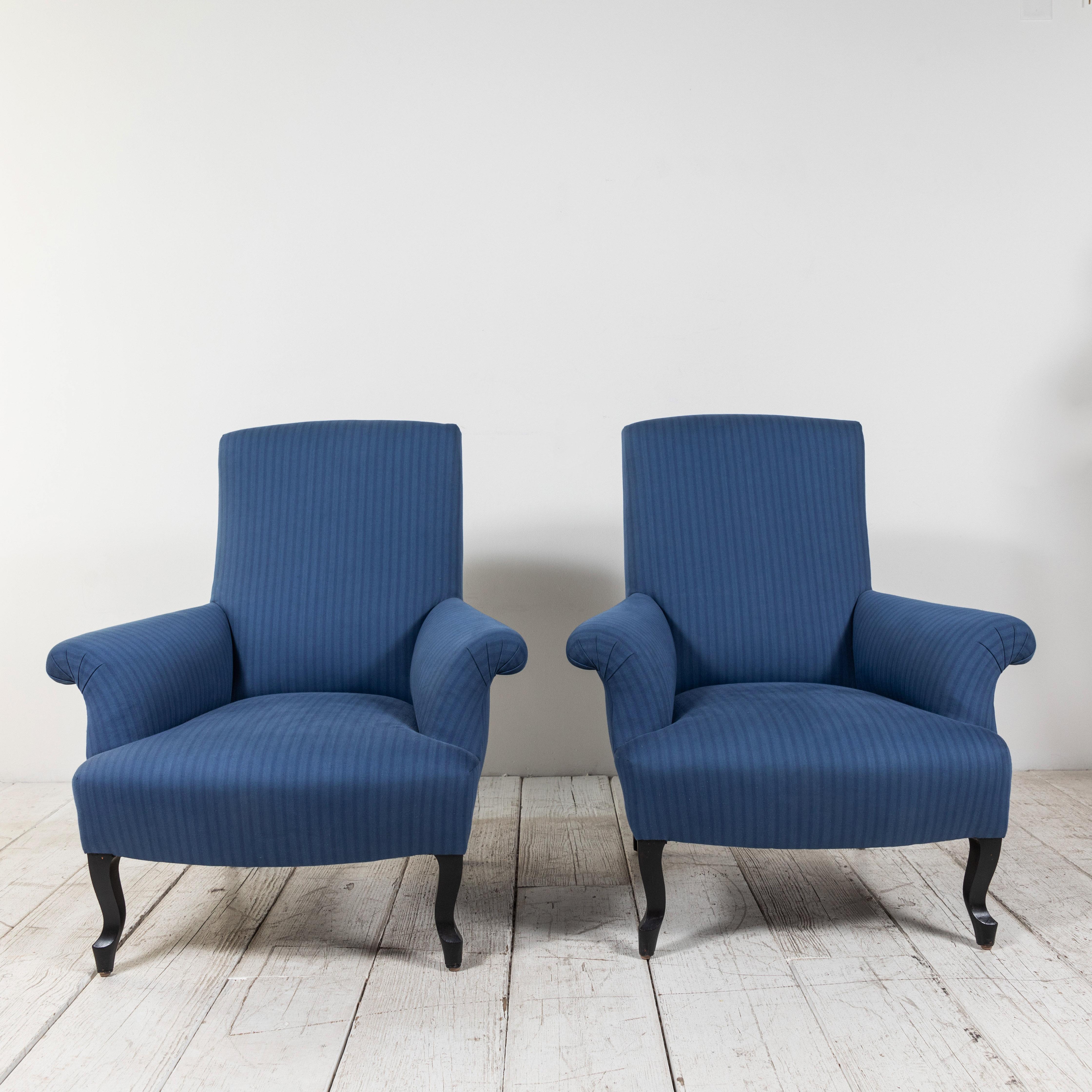 Classic pair of French rolled arm club chairs upholstered in tonal blue striped fabric from Howe of London. Original base finish boasts vintage flair.
