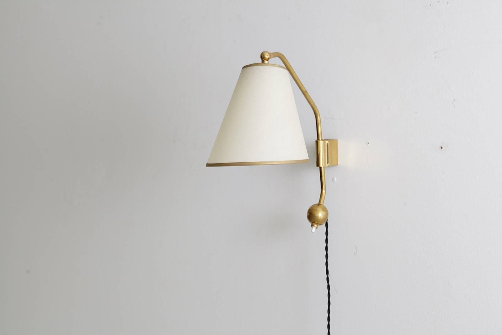 Beautiful brass French sconces in the style of Jean Royere. Counterbalance base with on/off switch rests on brackets to pivot. Conical silk shades with gold trim. Newly re-wired in French style with black silk twist cord.