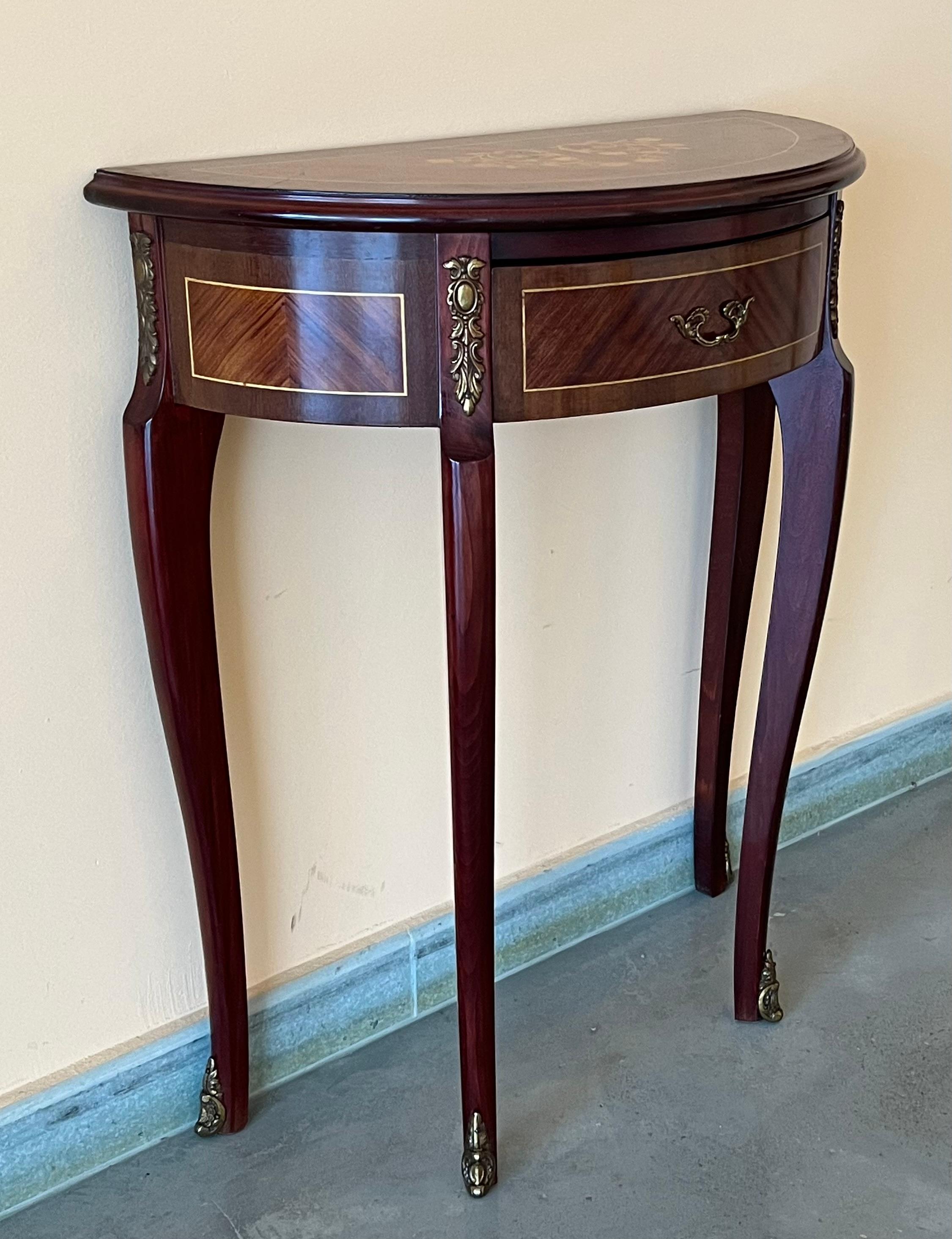 Elegant French inspired satinwood demilune console table with fine classical Floral marquetry inlay on the top, drawer and sides, raised on tapering legs with brass details.
You can use as nightstands, console, or side table.