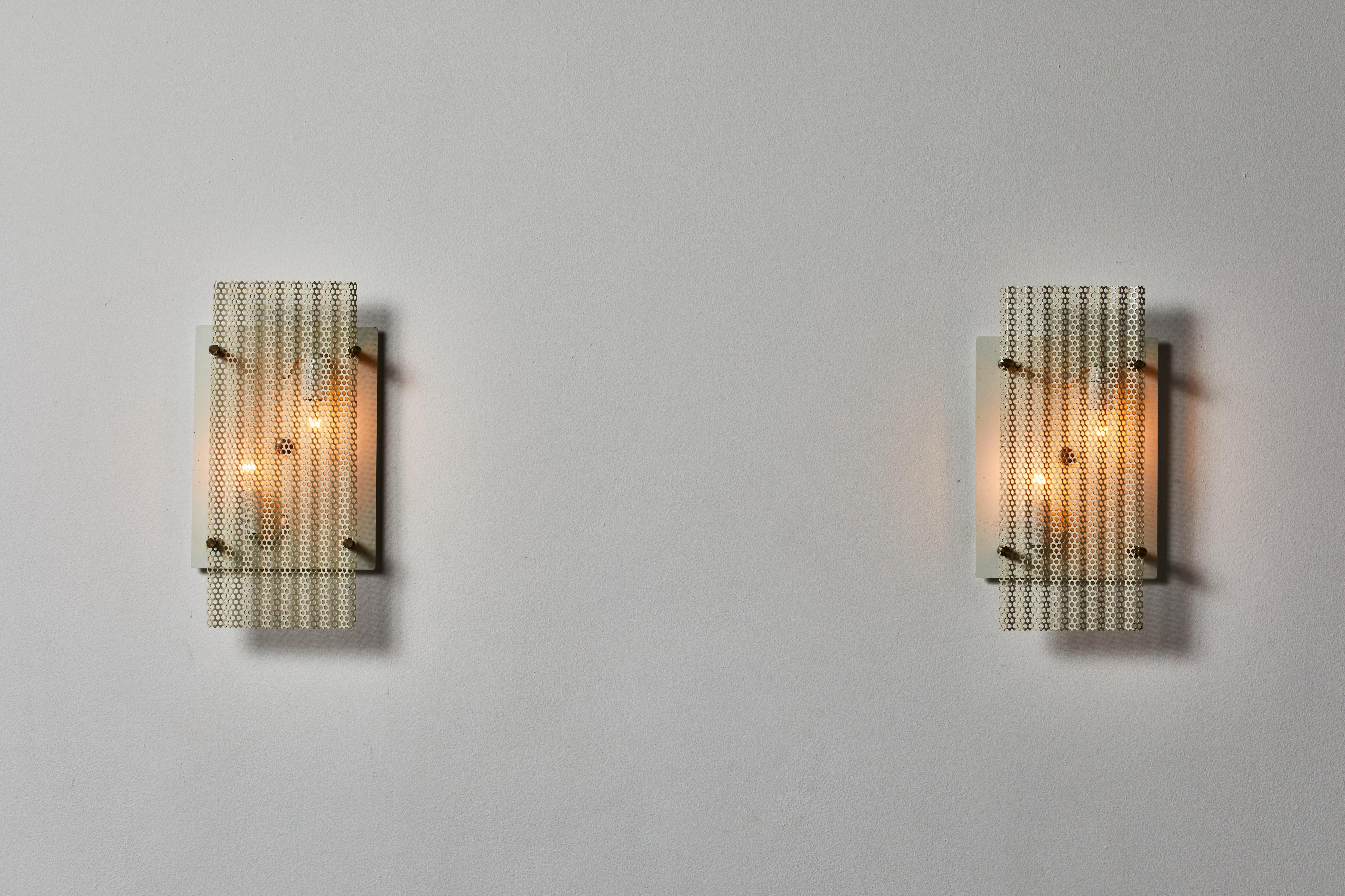 Pair of sconces manufactured in France, circa 1950s. Original painted perforated aluminum, brass. Wired for U.S. standards. We recommend two E14 40w maximum candelabra per fixture. Bulbs provided as a one time courtesy.