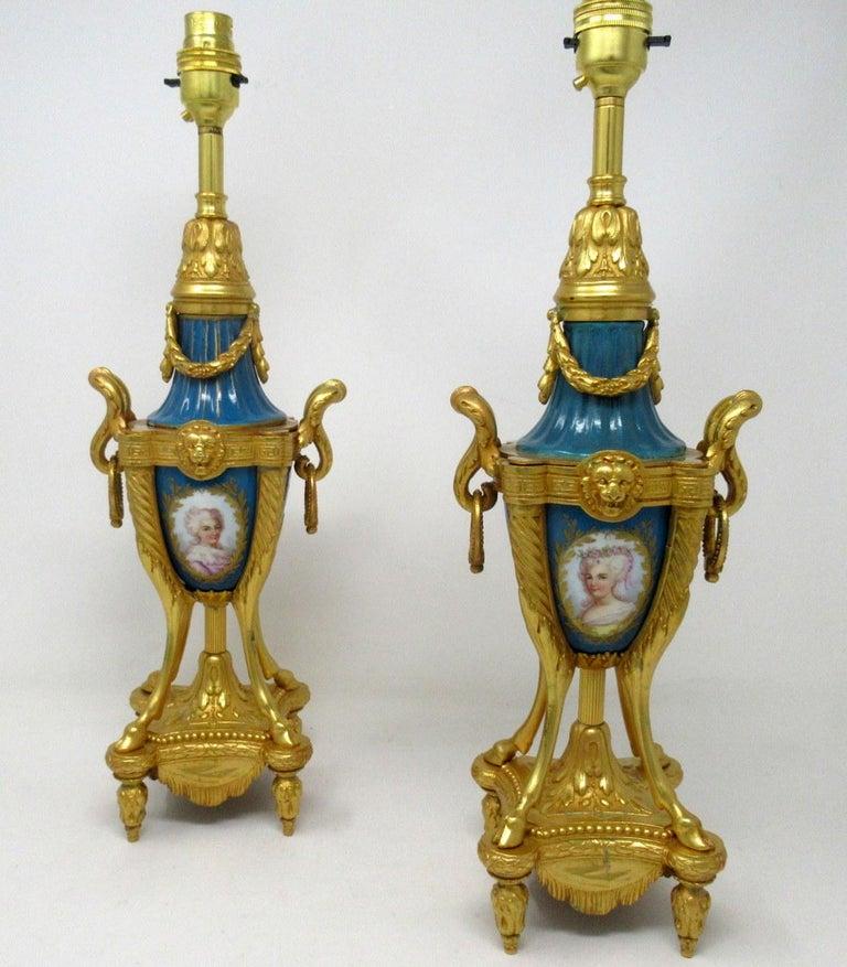 Stunning pair of French Sèvres soft paste porcelain and gilt metal Ormolu twin handle electric table lamps of traditional urn form, and of good size proportions, raised on four slender outswept supports ending on hoof feet on an ornate inverted