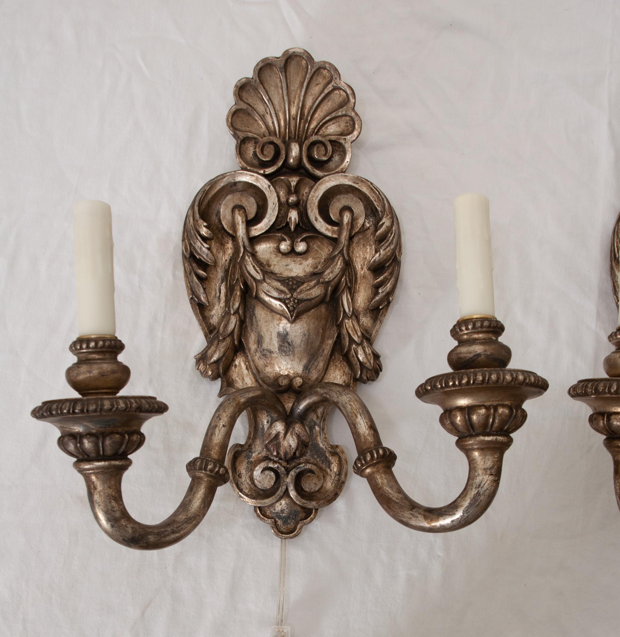 An elegant pair of silver gilt wall sconces hand-crafted in France in the 20th century. Each of these lustrous sconces features beautiful hand-carved shell motifs at the pediment, scrolling motifs, acanthus leaves embellishment, and bellflowers