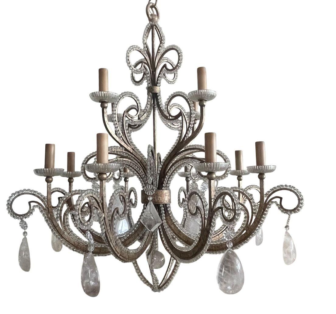 Stunning pair of French wrought iron chandeliers, finished in antique silver leaf and adorned with rock crystal drops and crystal beading. Each chandelier features gracefully scrolled arms with elegant detailing, combining refined craftsmanship with
