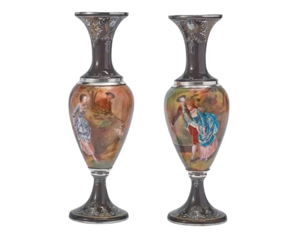 A pair of French silver & Limoges enamel vases, retailed by Tiffany & Co., 19th century.

The silver mounts with JC hallmarks, for Joseph Cousin, Paris.

The first painted with a couple next to a rowboat with a castle in the distance, the second