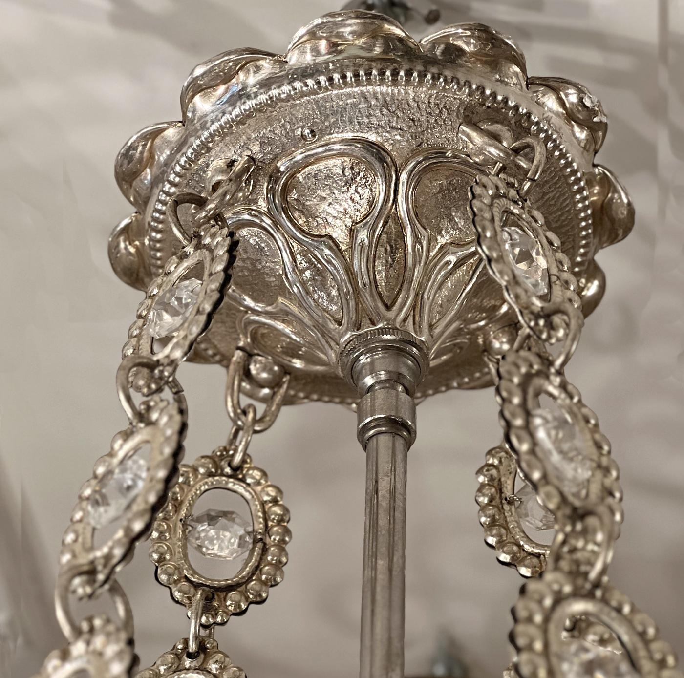 A pair of French circa 1950s silver-plated flower-shaped bronze chandeliers with crystal drops, flowers and beads on body and ten interior candelabra lights.

Measurements:
Diameter: 40