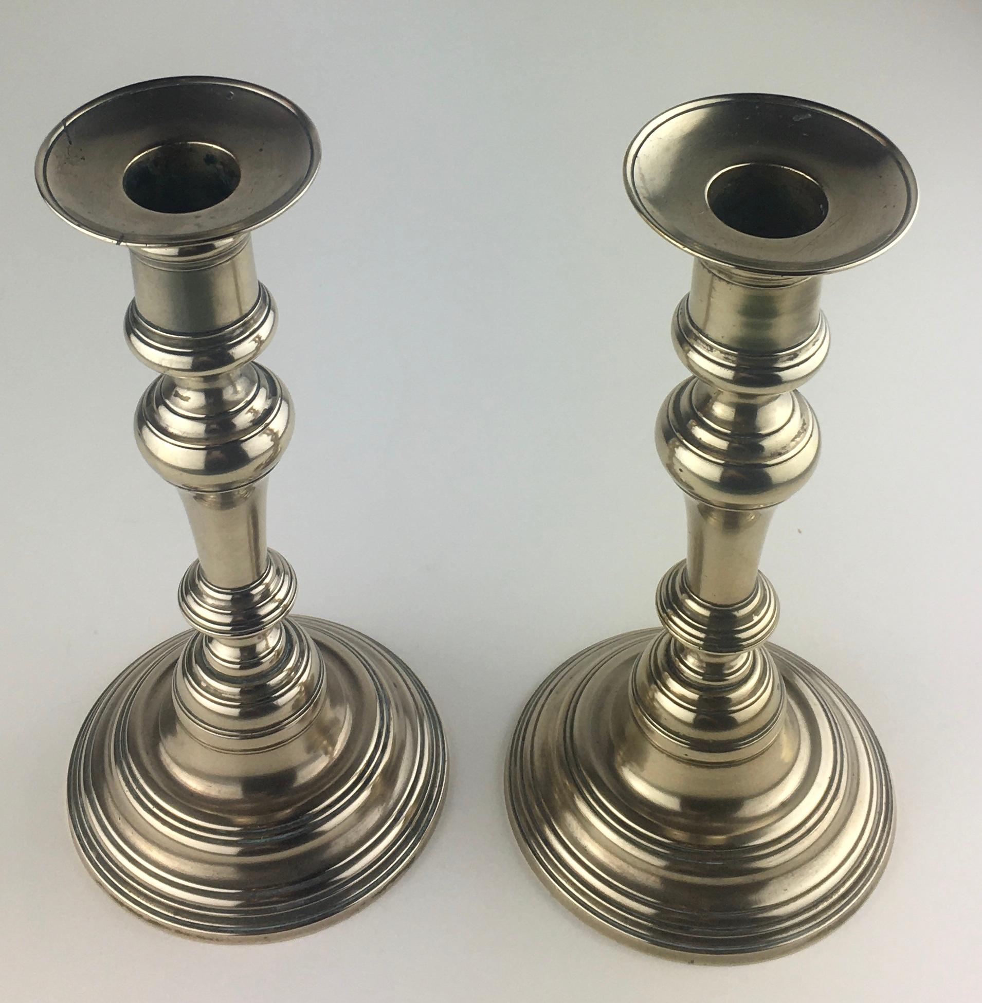 Charming pair of French solid brass candlesticks. 
These simple yet beautifully detailed items will enhance any coffee, cocktail or bedside table. 

Very good condition overall. One base has been drilled to convert into a table lamp and the bobeches
