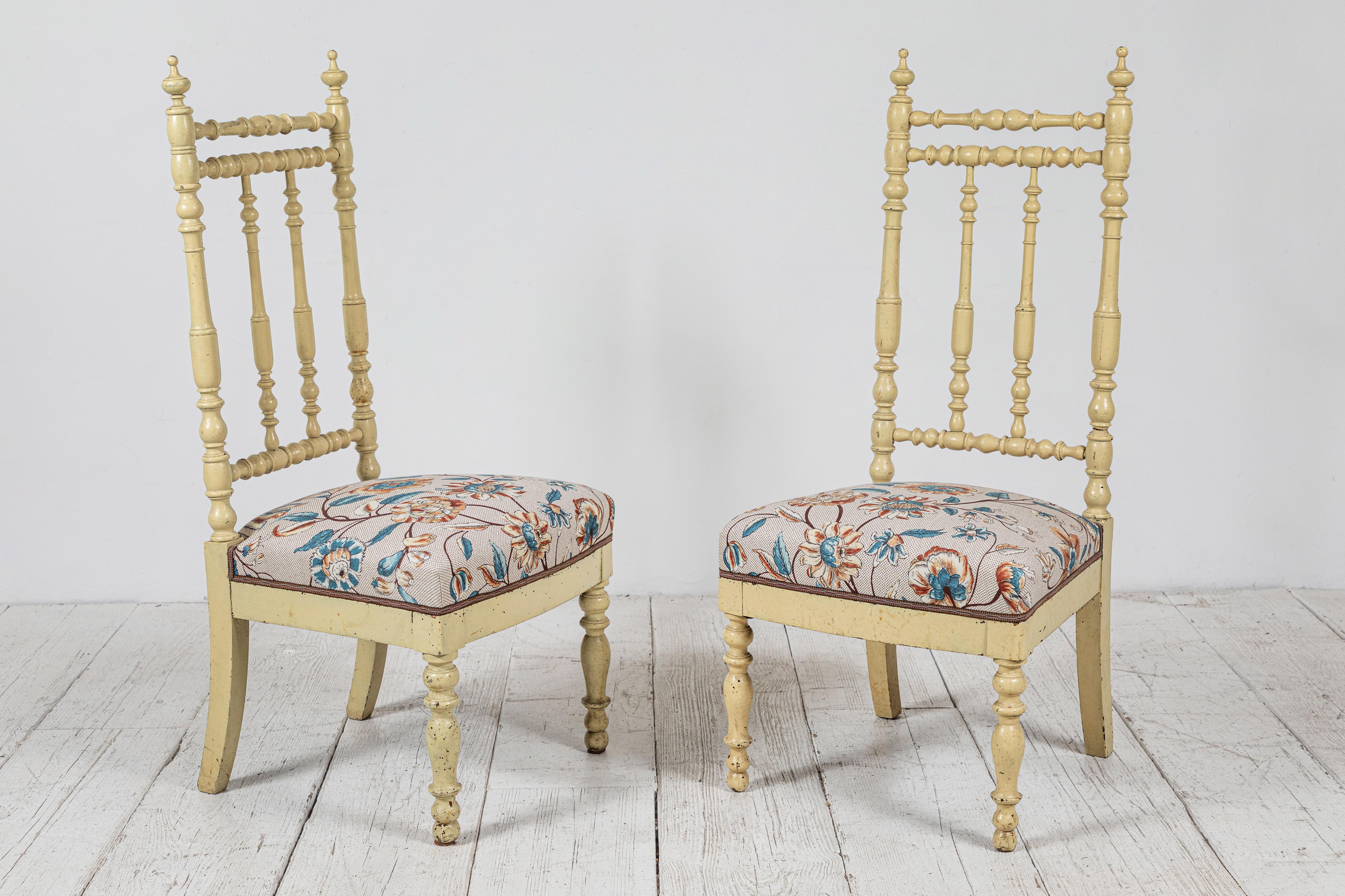 Pair of beautiful French spindle chairs with original cream colored painted frame. Seat cushions newly upholstered in Claremont floral linen with vintage tape trim.