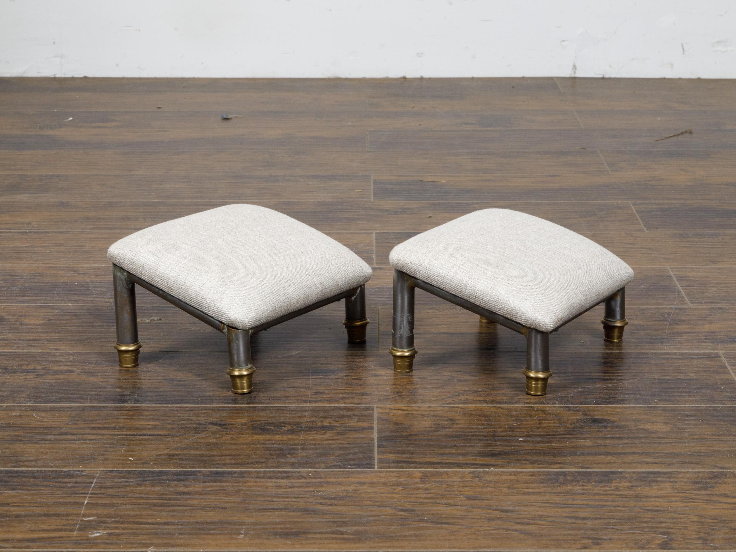 Paire de poufs français en acier et basse avec tapisserie en lin personnalisée. Cette exquise paire de poufs français allie l'élégance de l'acier et du laiton au confort d'un revêtement en lin personnalisé. Les pieds cylindriques constituent une