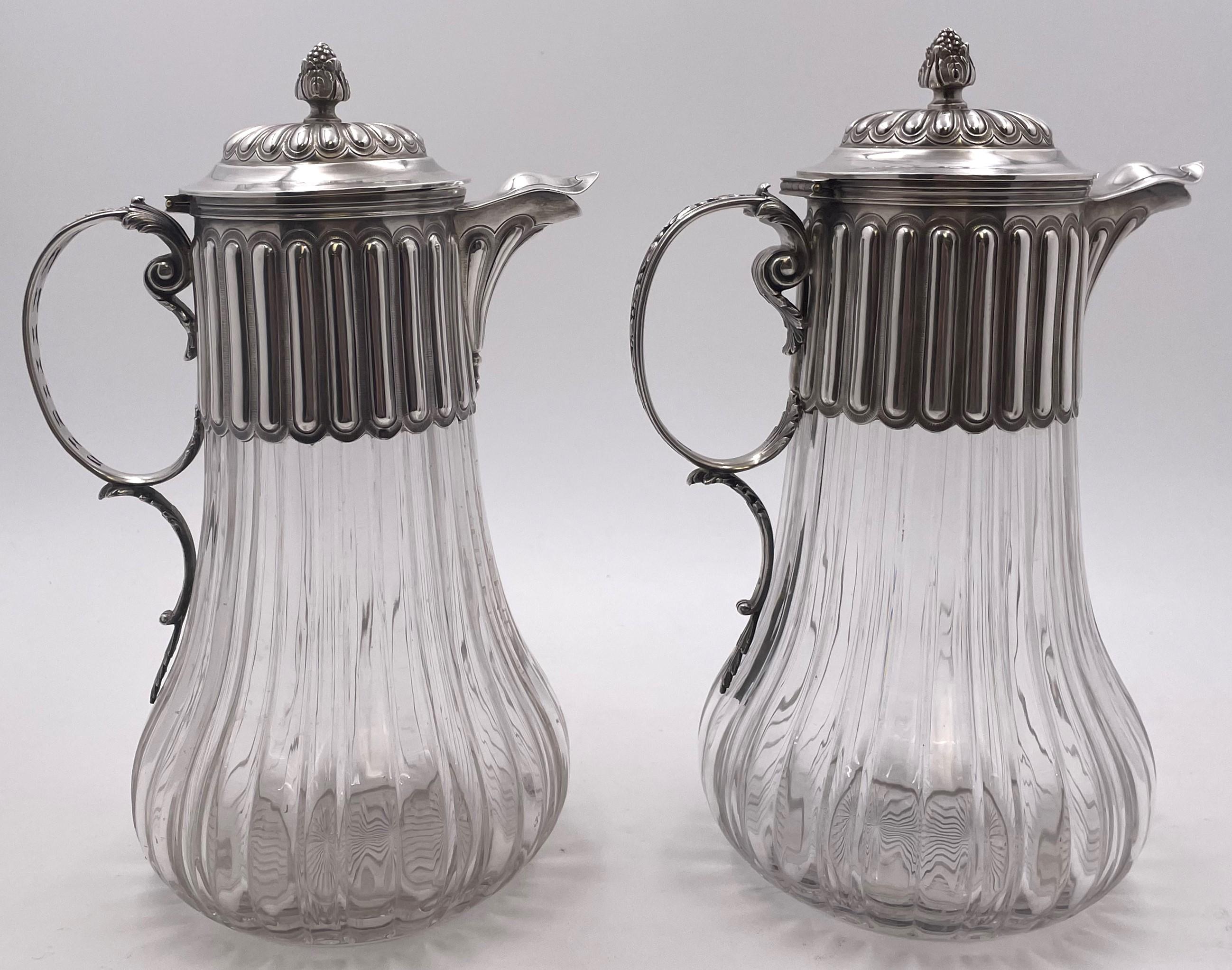 Paire de carafes ou pichets français en argent 0,950 (pureté supérieure à celle de l'argent) et verre taillé de la fin du XIXe siècle, avec d'exquis motifs géométriques et naturels stylisés. Ils mesurent 11 1/3'' de hauteur par 7 2/3'' de l'anse au