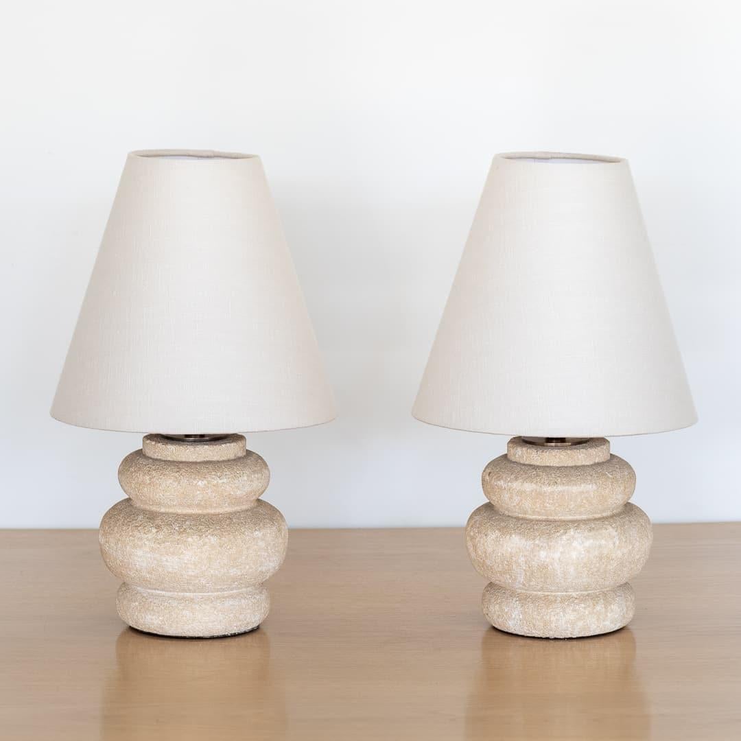 Great pair of vintage stone table lamps from France, 1950's. Heavy, natural-colored curvy stone base with new off-white tapered linen shades.  Newly re-wired. Each takes one E12 base bulb, 40 W or higher using LED.

