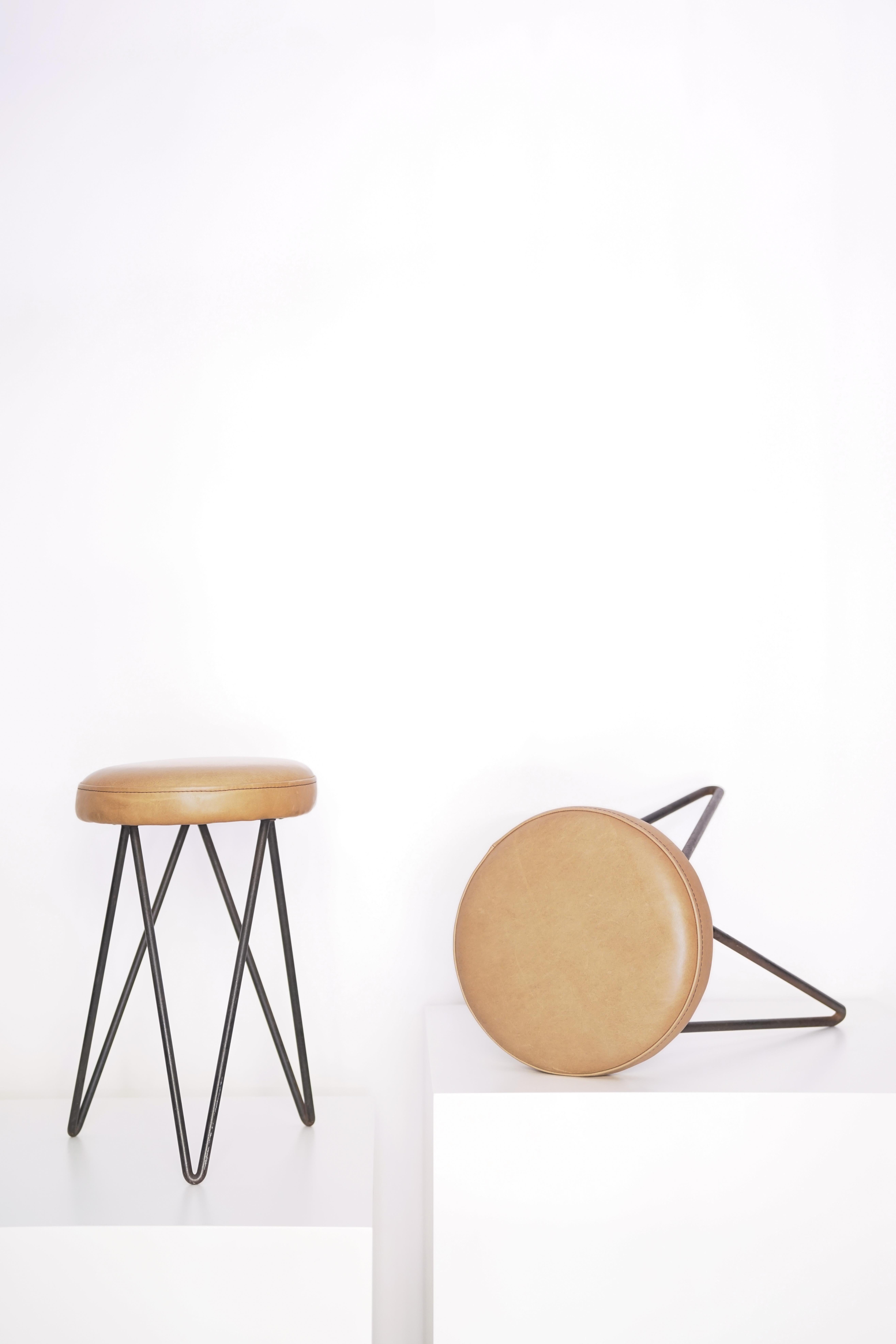 Paar französische Lederhocker, 1960er Jahre, entworfen von Pierre Guariche.

Über den Designer:
Als visionärer Designer hat er den Möbeln eine funktionale Dimension verliehen, ohne jemals den ästhetischen Ansatz zu vergessen. Er wollte auf die