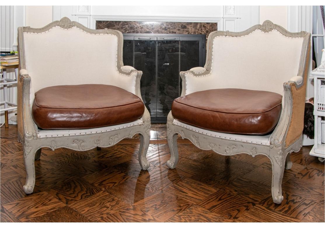 Pair of French Style Bergeres in a very Fine Custom Fabric with gray painted frames, pale linen backs, burlap backs and sides, and nail head decorations. Web seat construction. With brown leather seat cushions. 
Dimensions: 29