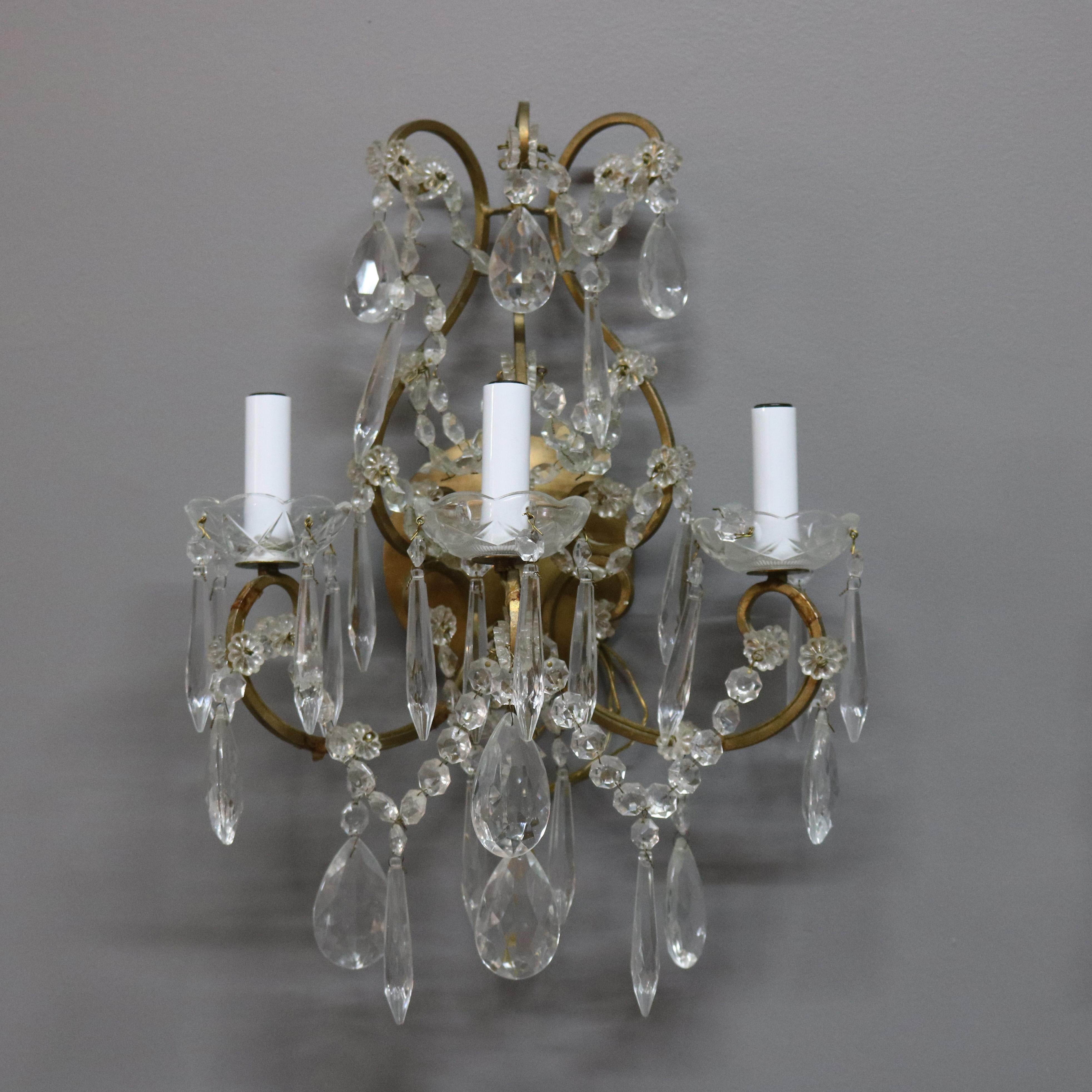 A vintage pair of French wall sconces offer brass scroll form frame with three arms terminating in candle lights, strung and hanging cut crystals throughout, circa 1940.

***DELIVERY NOTICE – Due to COVID-19 we are employing NO-CONTACT PRACTICES in