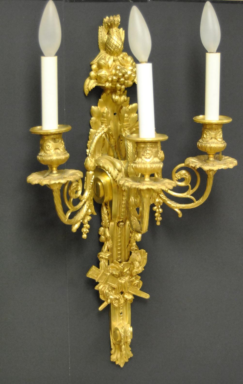 Stunning pair French style gold doré bronze three socket sconces. Twisted arms with grape clusters details. Fruit designs at the top featuring pineapple, grapes and apples. Three-dimensional rose reliefs at the bottom. Two pair are available. Price
