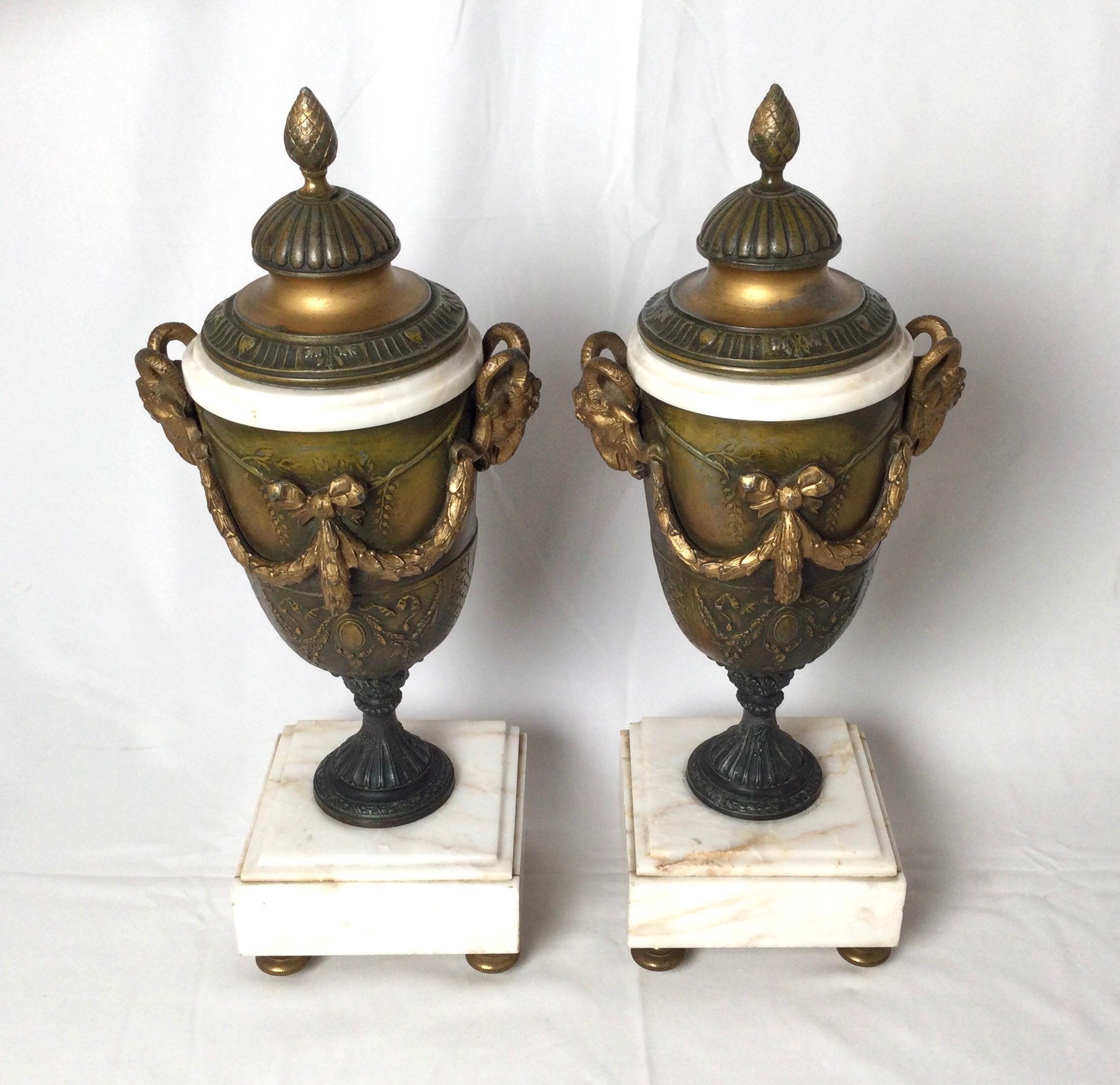 Pair of French style marble and patinated metal garniture urns with ram heads.
Late 19th century, with high relief decorations and attached lid.
Dimensions: 15