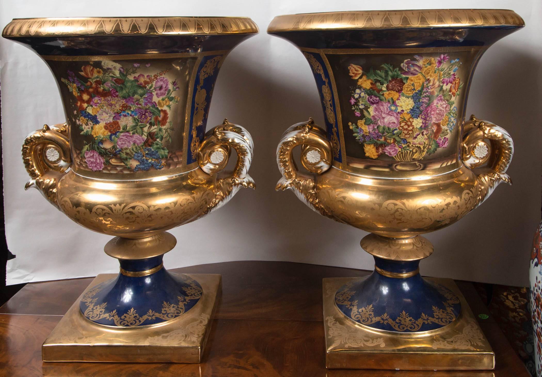 Campana form porcelain urns decorated in cobalt blue, white and gilt. Each side with a panel of bouquets of flowers.
Indecipherable mark on bottom.