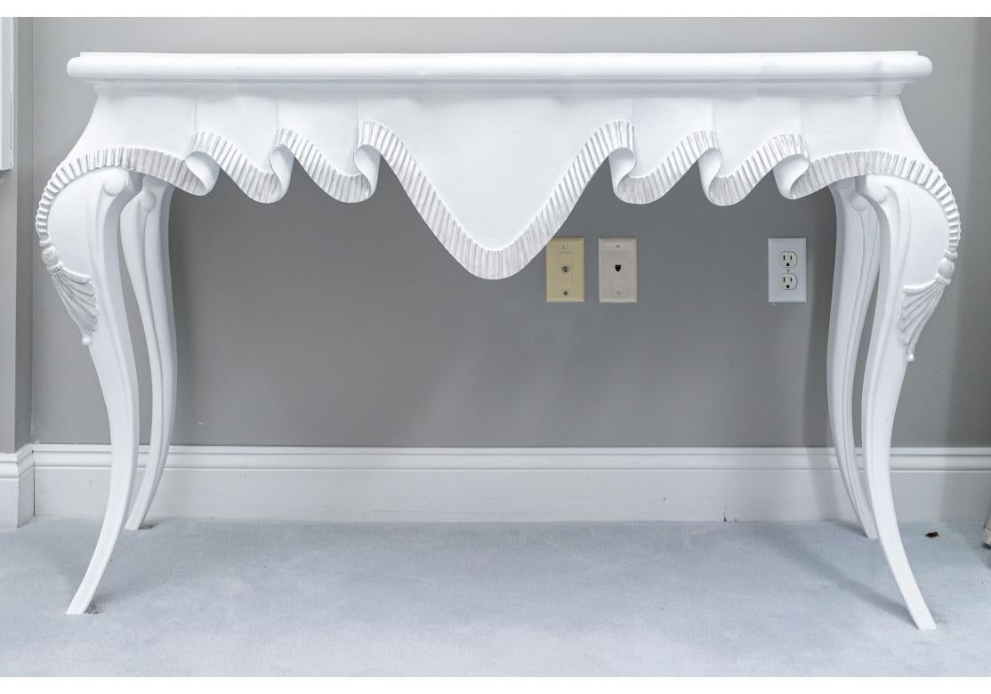 An extraordinary Pair of white paint decorated trompe l'oeil console tables with deep dimensional draped top. The drape with dramatic silver fluted trim with the concentric folds neatly stacked behind the center scallop. The tables further with
