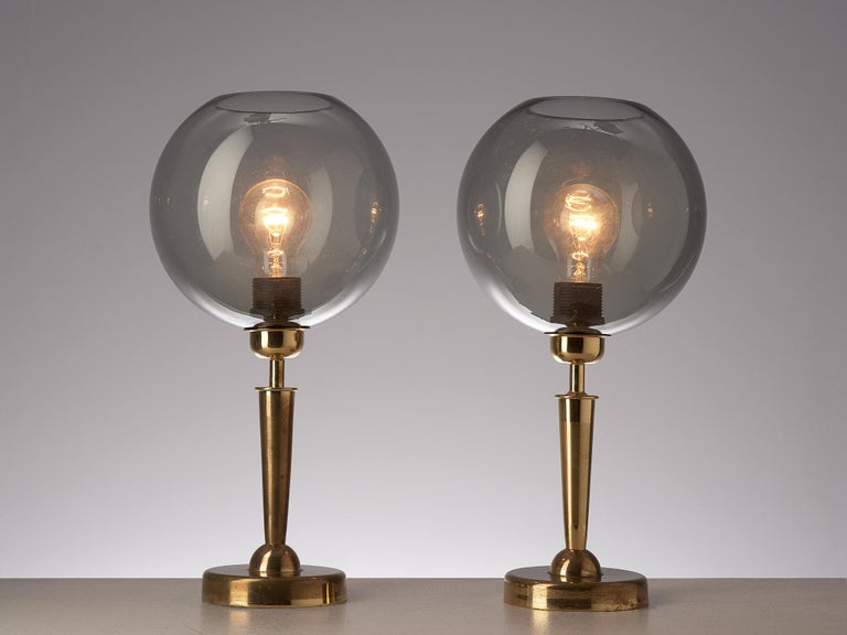 Table lamps, brass and glass, France, 1970s

These table lamps are composed of a spherical shade executed in smoked glass which enriches the radiation of the light in a fine manner. The creator implemented well-designed geometric forms in the lower