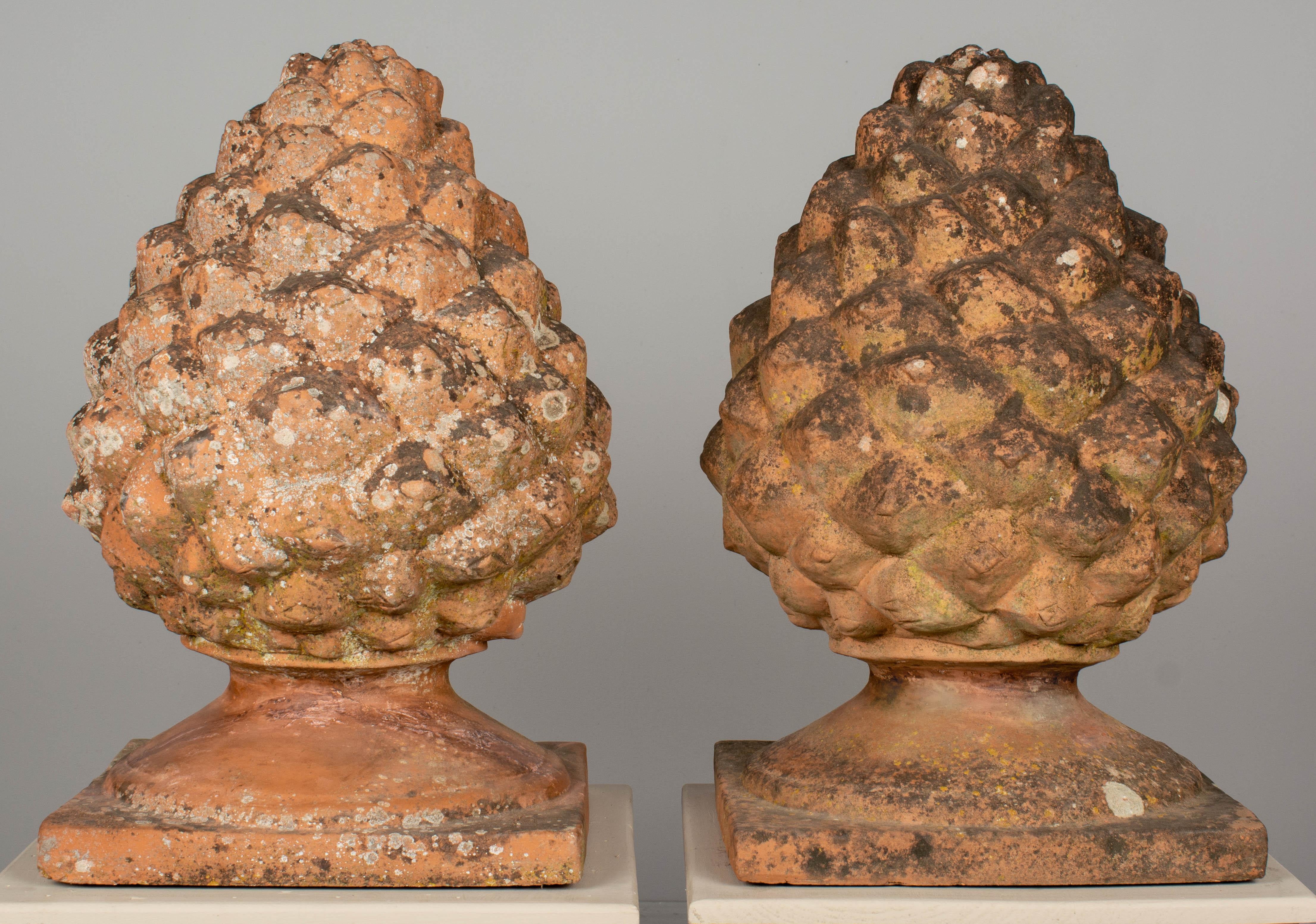 A pair of large French terracotta architectural garden pinecone finials with beautiful weathered mossy patina. Perfect for use as ornamental elements in the garden or to flank an entryway. Each with old restorations on the base. Very good quality,