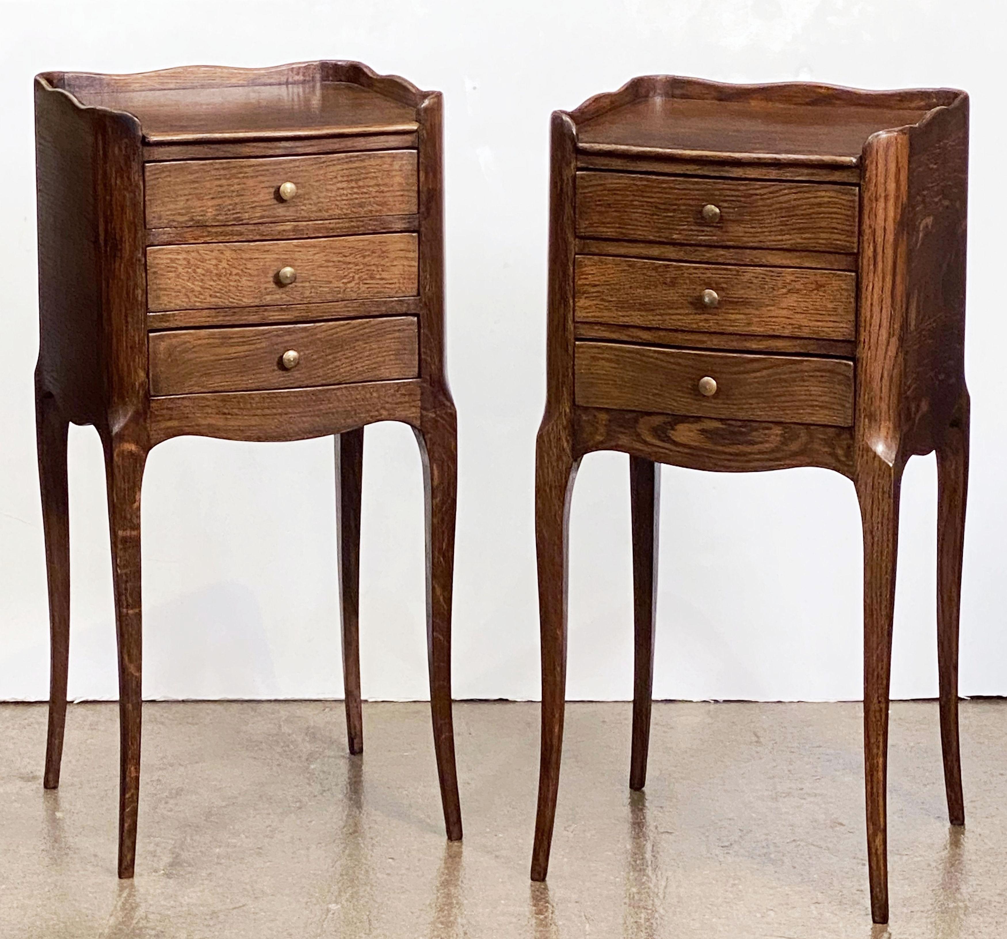 A fine pair of French bedside end tables or nightstands of oak, each stand featuring with scalloped edge gallery over a frieze of three drawers with brass pulls, apron bottom, and set upon four tapering cabriole legs.

Priced as a pair - $3895 the