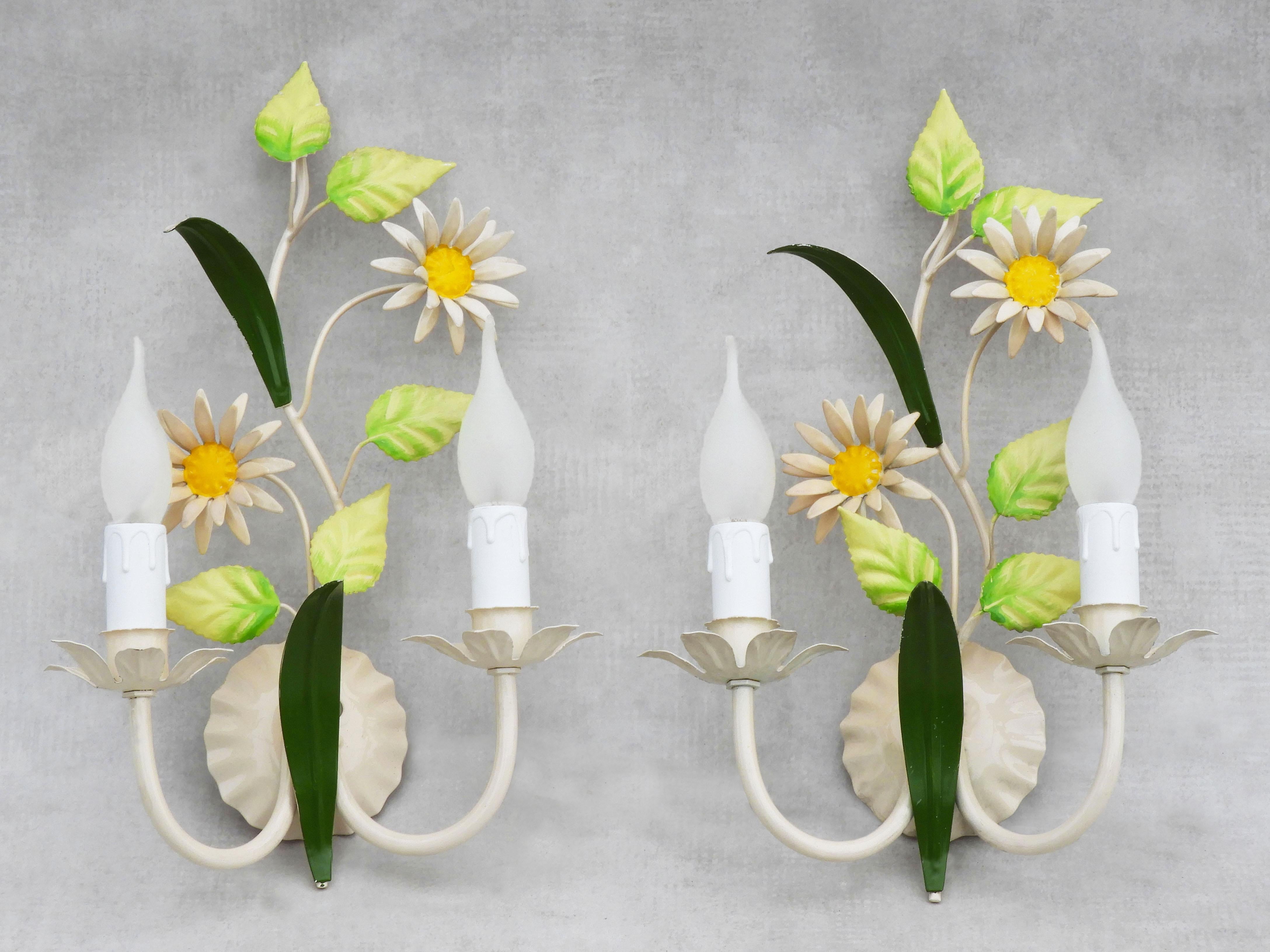 Pair of French Tôle Flower Wall Light Sconces, c1960

A pretty duo pair of mid-century enamelled tôleware wall lights each decorated with Marguerite Daisy blooms, glossy green foliage and two faux candlelights.
In nice vintage condition with good