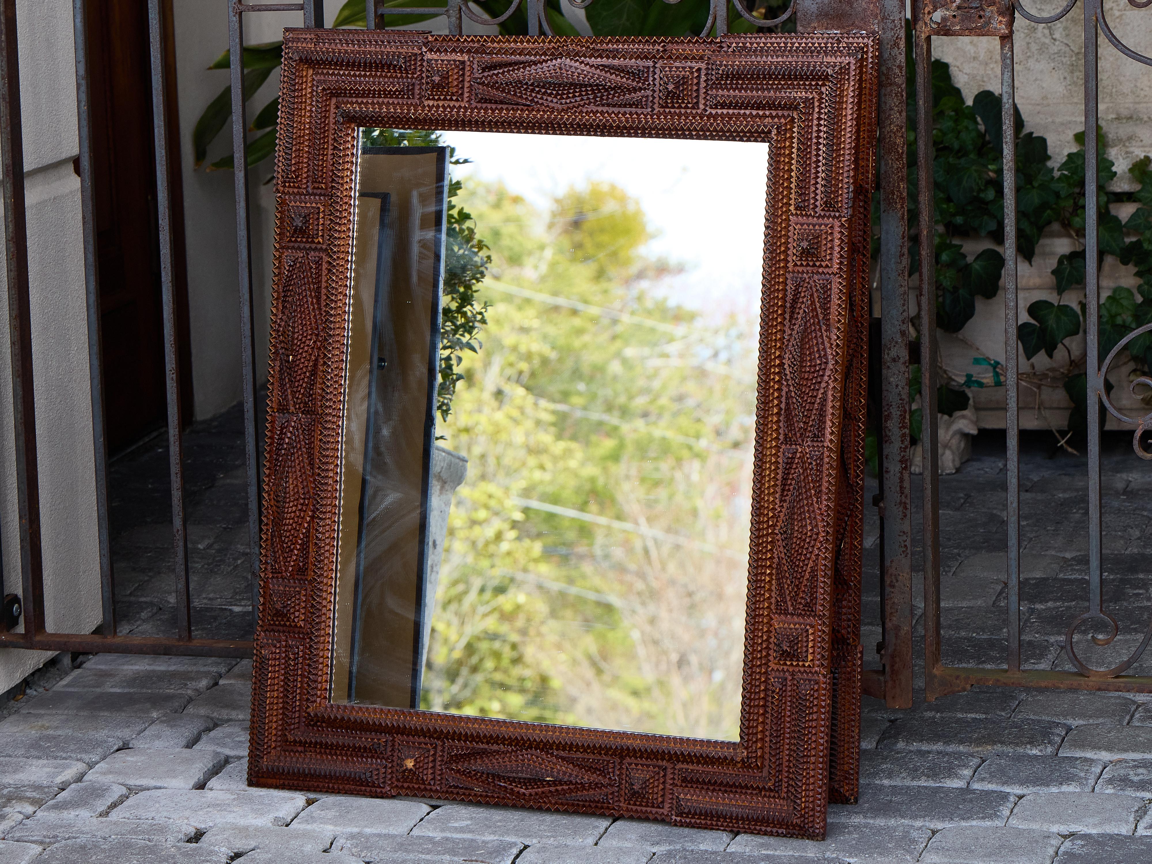 This pair of French Tramp Art mirrors, dating to circa 1900, offers a striking example of the genre’s intricately layered and hand-carved aesthetic. Each frame is built from repeated geometric forms—zigzags, notches, diamonds—cut and stacked in