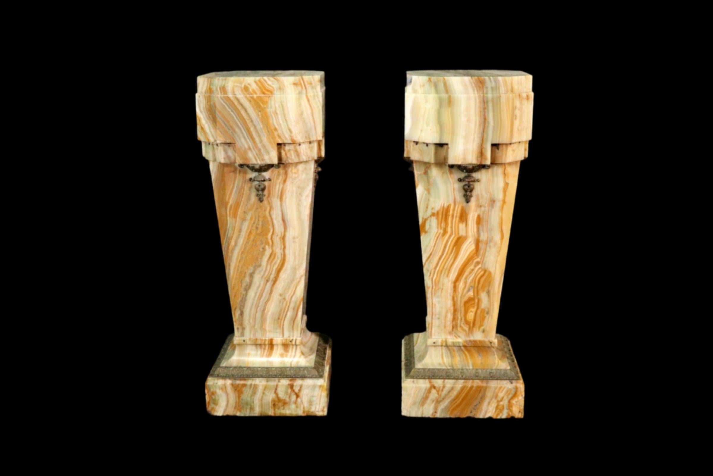 Onyx. Bronze accents. pair of pedestal stands. Chips and old losses of onyx. Bronze ormolu from the Louis XVI transtion towards French Art Deco.

DImensions: 33