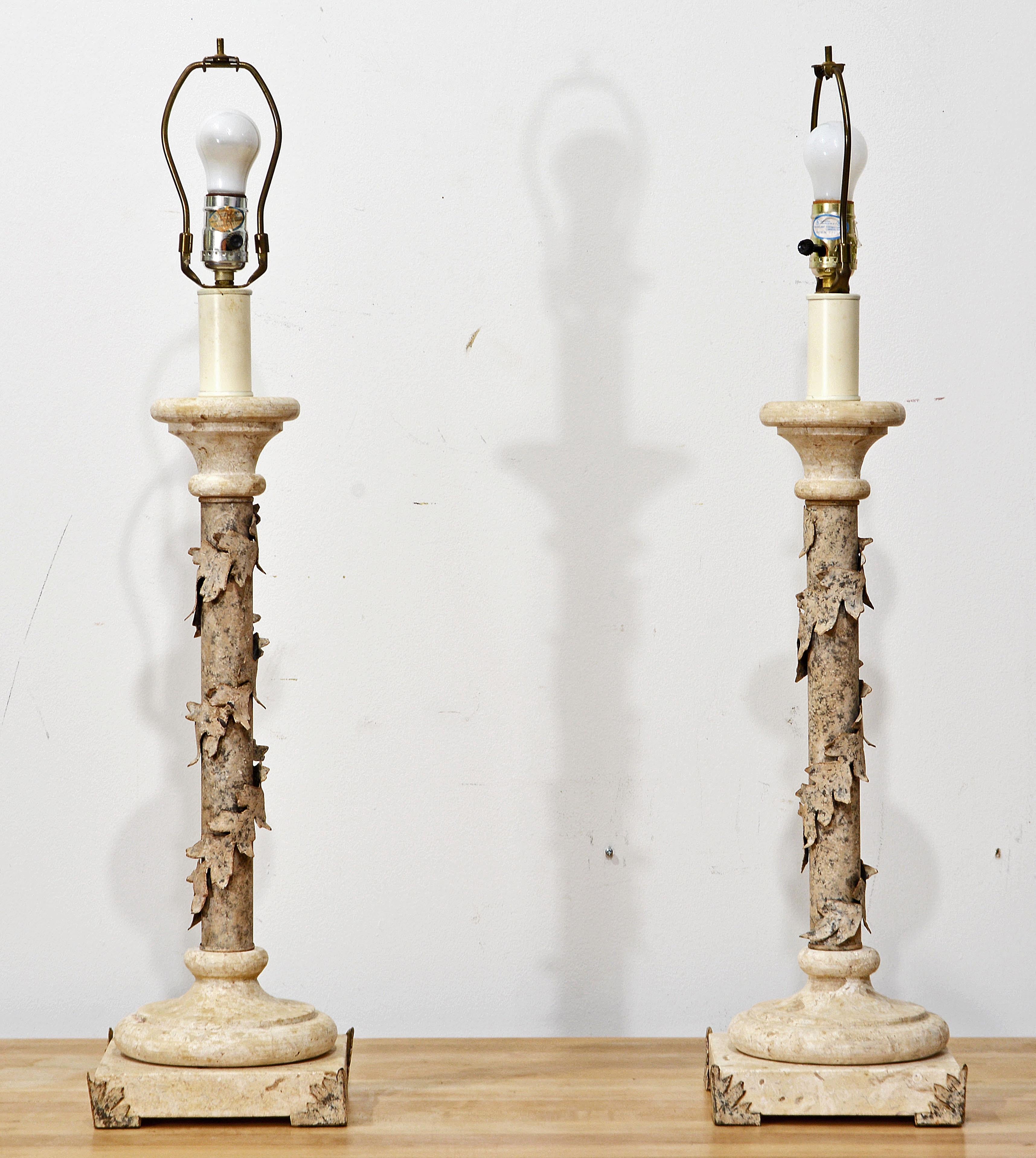 This pair of unique French Table lamps consist of stepped fossil filled Travertine type marble bases mounted with ivy leaf shaped corner ornaments from witch the the metal columns raise adorned by spiraling ivy garlands, all painted to an attractive