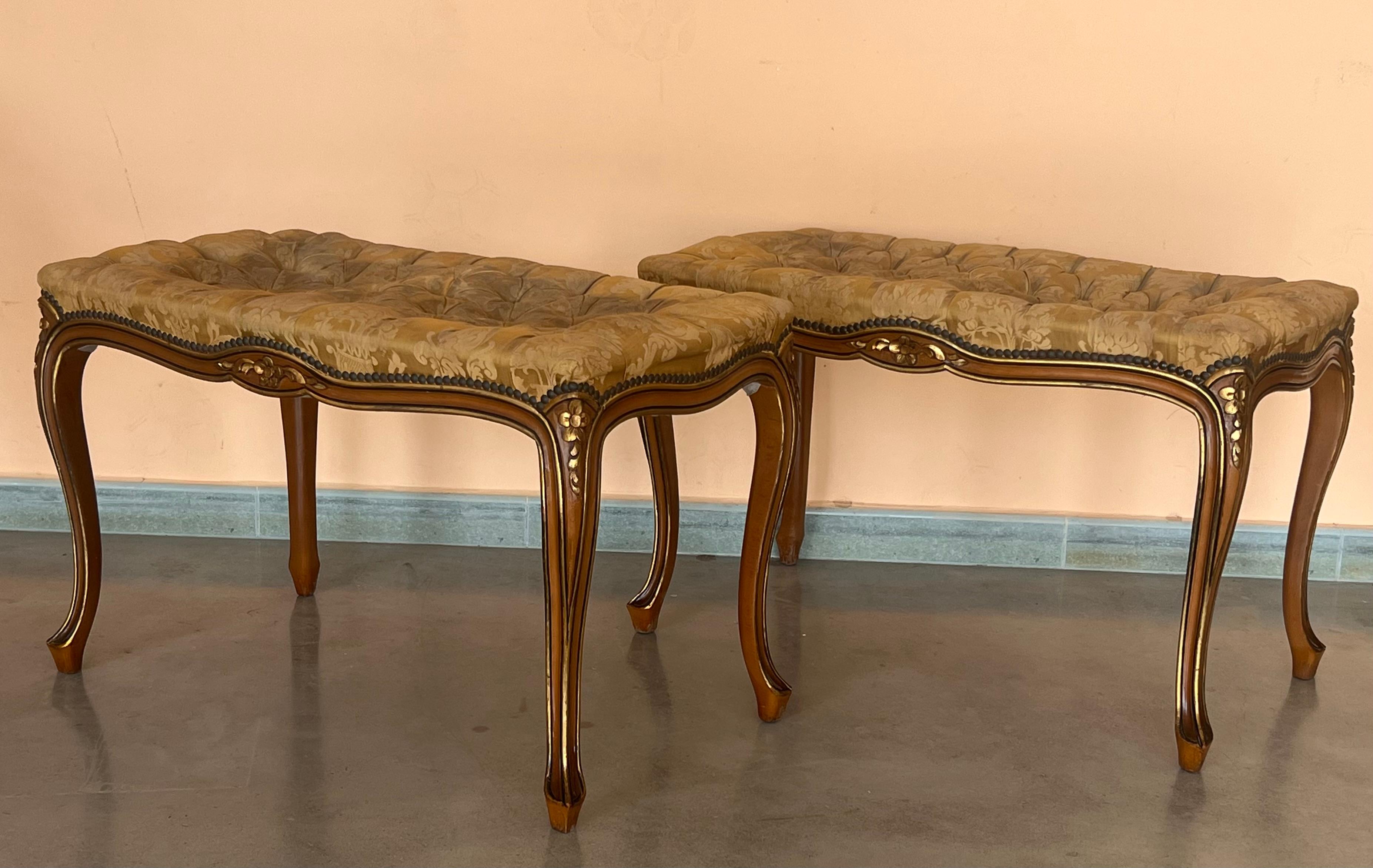 Pair of tufted French Louis XV style benches. There are beautiful carved details throughout. The bench stands on four cabriole legs that end in rams head feet. They are upholstered in dams that has some wear but no tears or damage. It actually has a