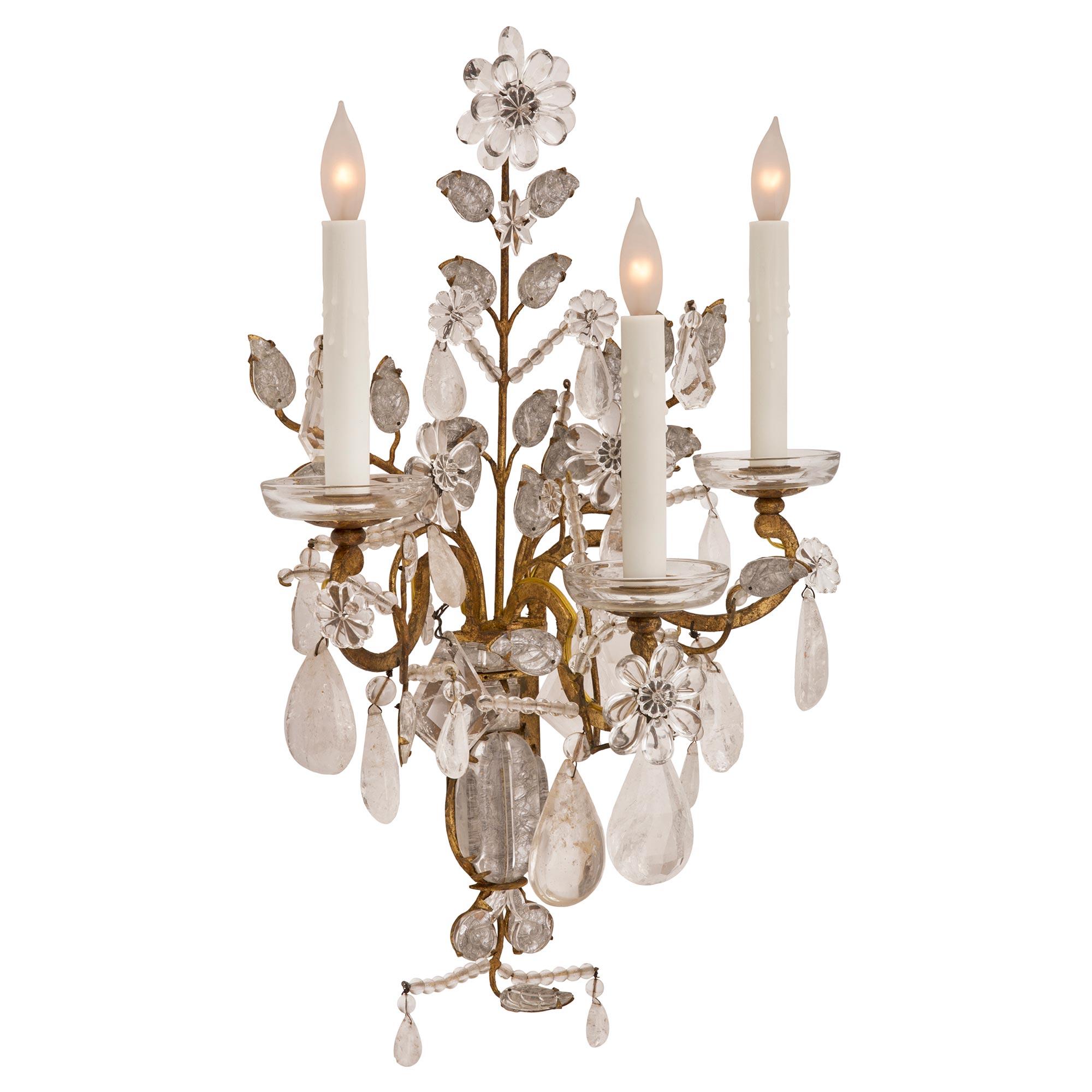 A charming and most decorative pair of French turn of the century Louis XVI st. crystal, rock crystal, and gilt metal sconces attributed to Maison Baguès. Each three arm sconce is centered by lovely leaf and beaded designs below the beautiful gilt