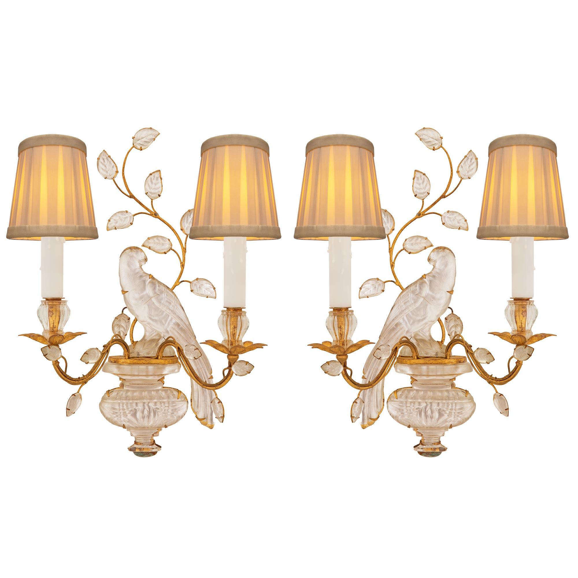 A beautiful true pair of French turn of the century Louis XVI st. gilt metal, silvered leaf, and crystal sconces attributed to Maison Bagues. Each two arm sconce displays a beautiful bottom crystal urn with a lovely mottled design set on a silvered