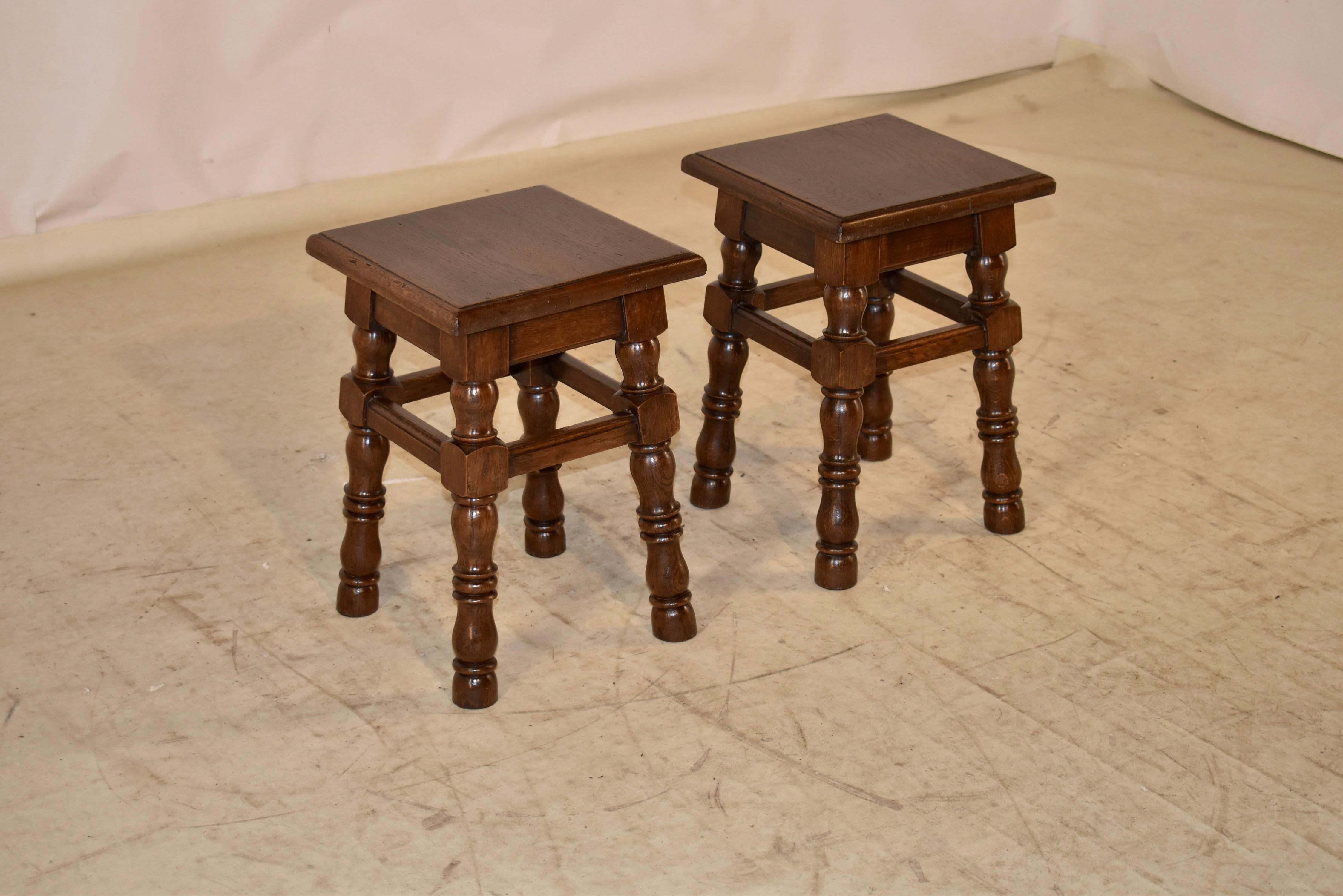 Pair of turned oak stools from France, circa 1900.  The seats have beveled edges and follows down to simple aprons and hand turned splayed legs, joined by simple stretchers with molded edges.  