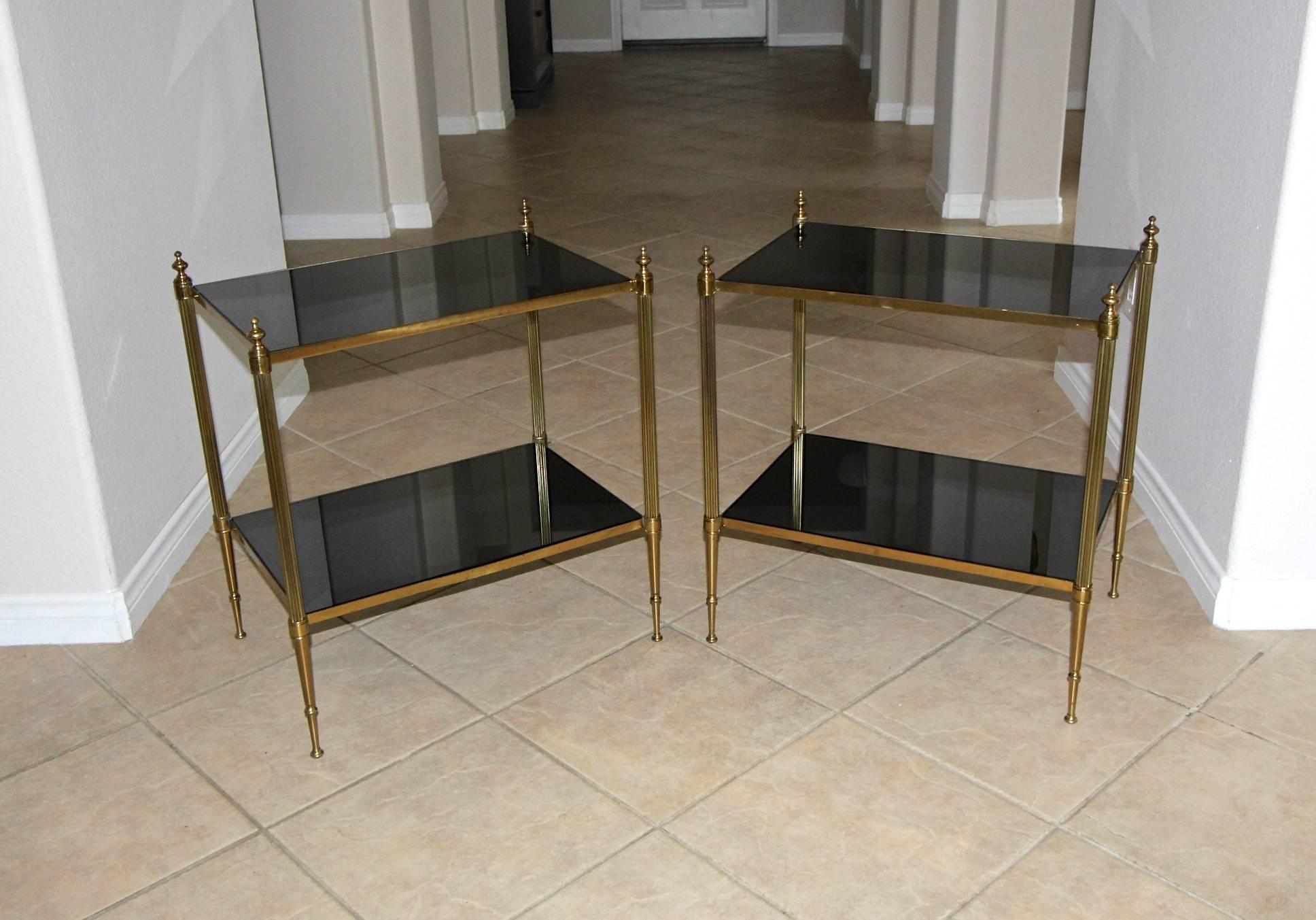 A pair of French two-tier brass side tables with newer dark graphite color mirrored inset tops.