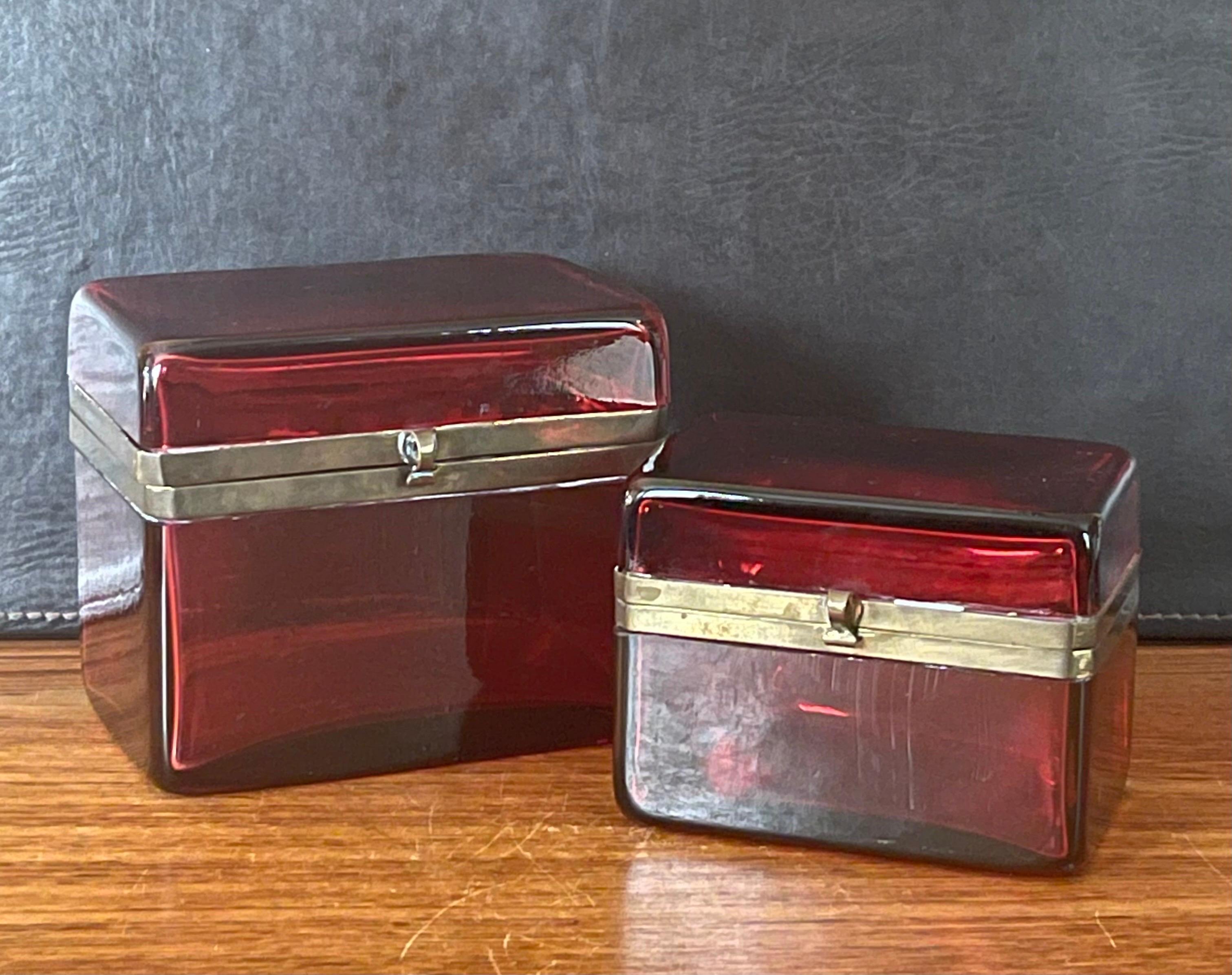 A fabulous pair of French Victorian era cranberry glass lidded boxes, circa late 1800's. The boxes are made of a thick cranberry colored glass with bronze dore latch and trim. The set is in very good antique condition with no chips or cracks; the