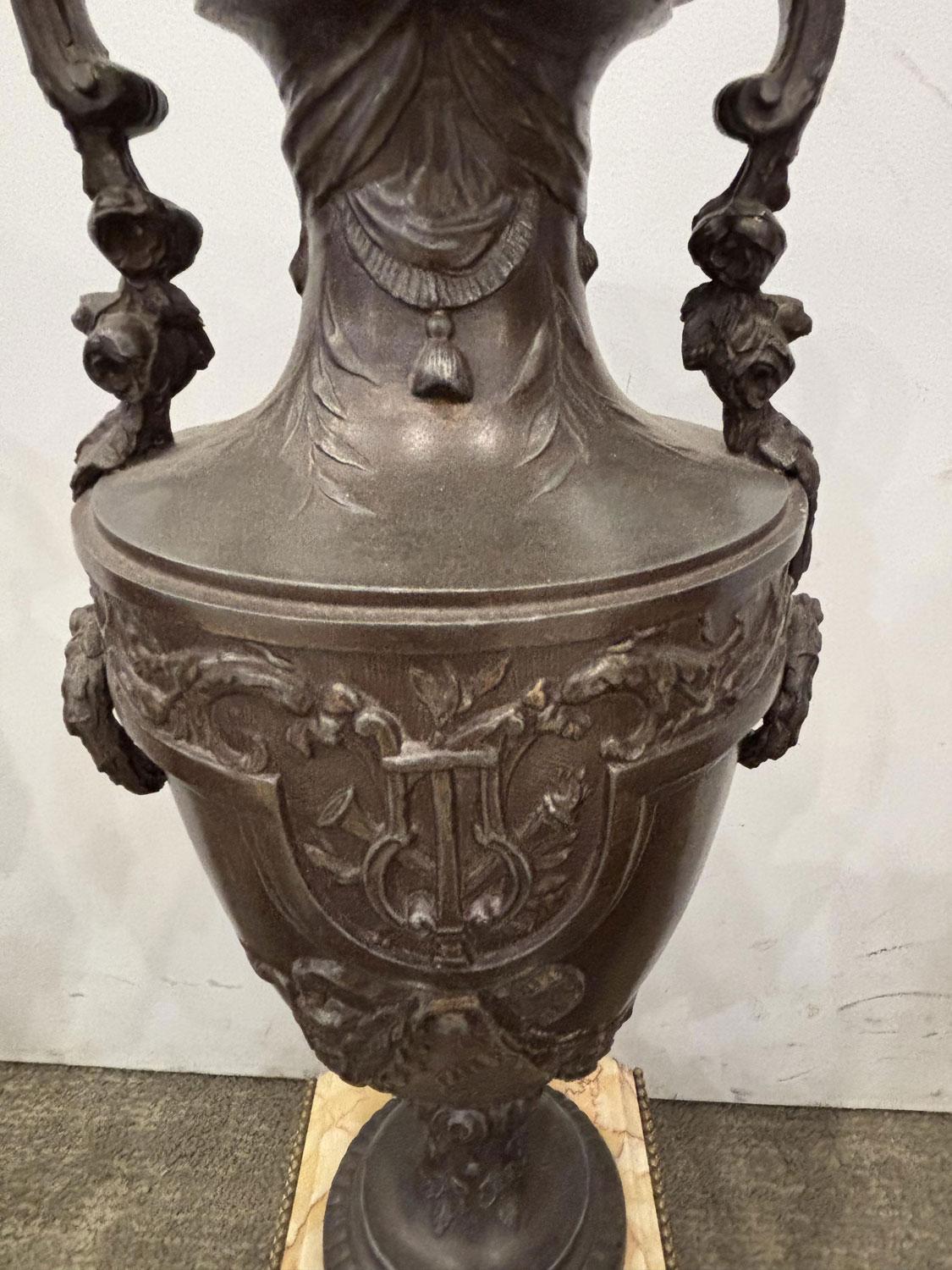 COPPIA di urne francesi vittoriane (fine del XIX secolo) in metallo con patina di bronzo e disegno a rilievo con manici floreali, sollevate su una base quadrata in marmo giallo con piedini in metallo (PREZZO A COPPIA)