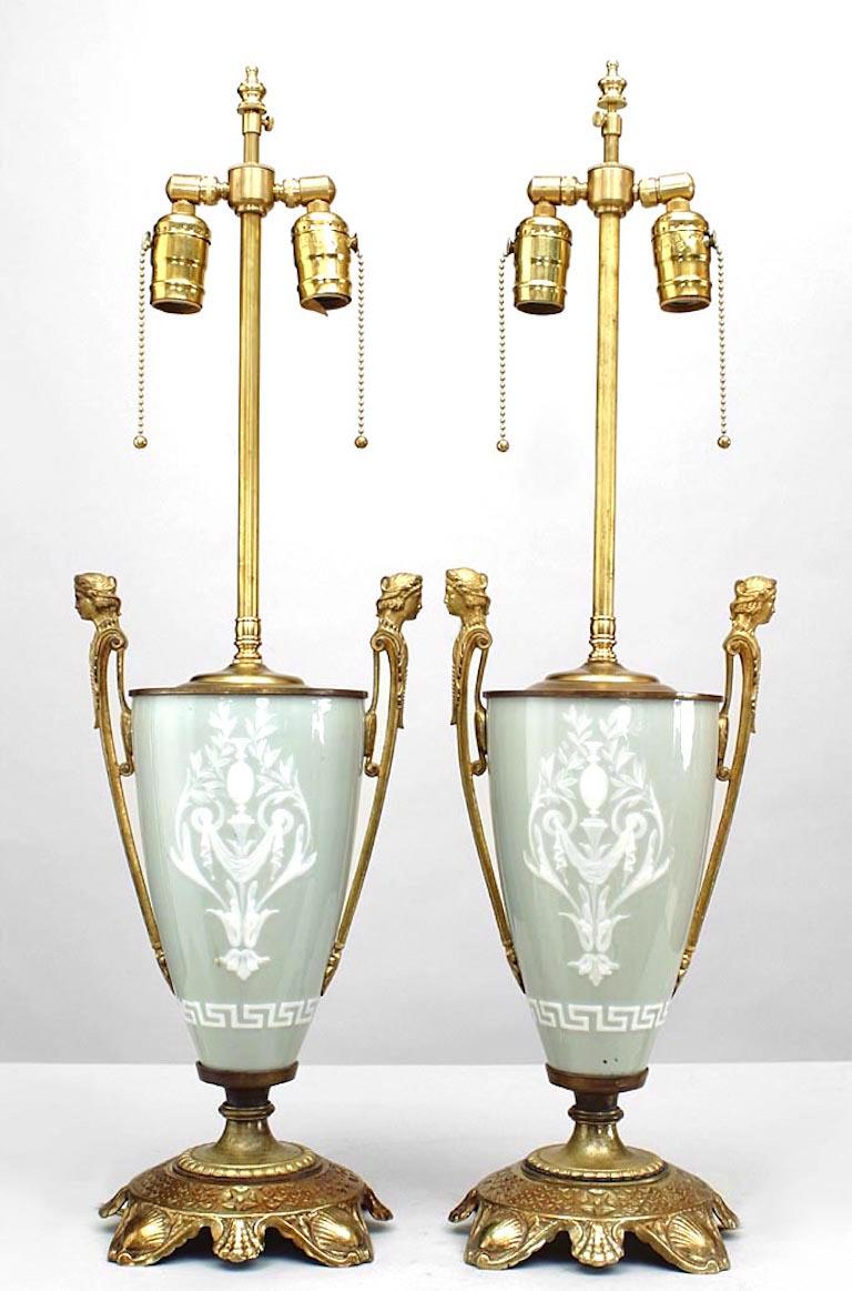 Pair of French Victorian green and white p√¢te-sur-p√¢te porcelain urn shaped table lamps with bronze handles with heads and shaped base (PRICED AS Pair).
