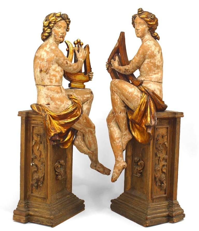 Ein Paar französischer viktorianischer Figuren in Lebensgröße, geschnitzt, Musikinstrumente spielend, mit vergoldeten Verzierungen und auf Sockeln sitzend.
  