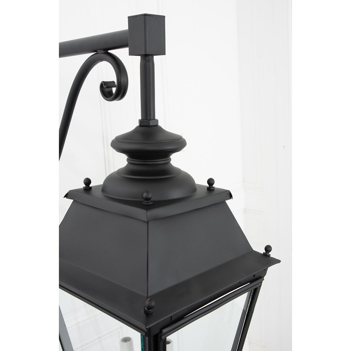 This pair of French vintage lanterns have been cleaned, powder coated and now have a weatherproof flat black finish. They are each suspended by their original decorative bracket. These lanterns have been rewired for US electrical using UL certified
