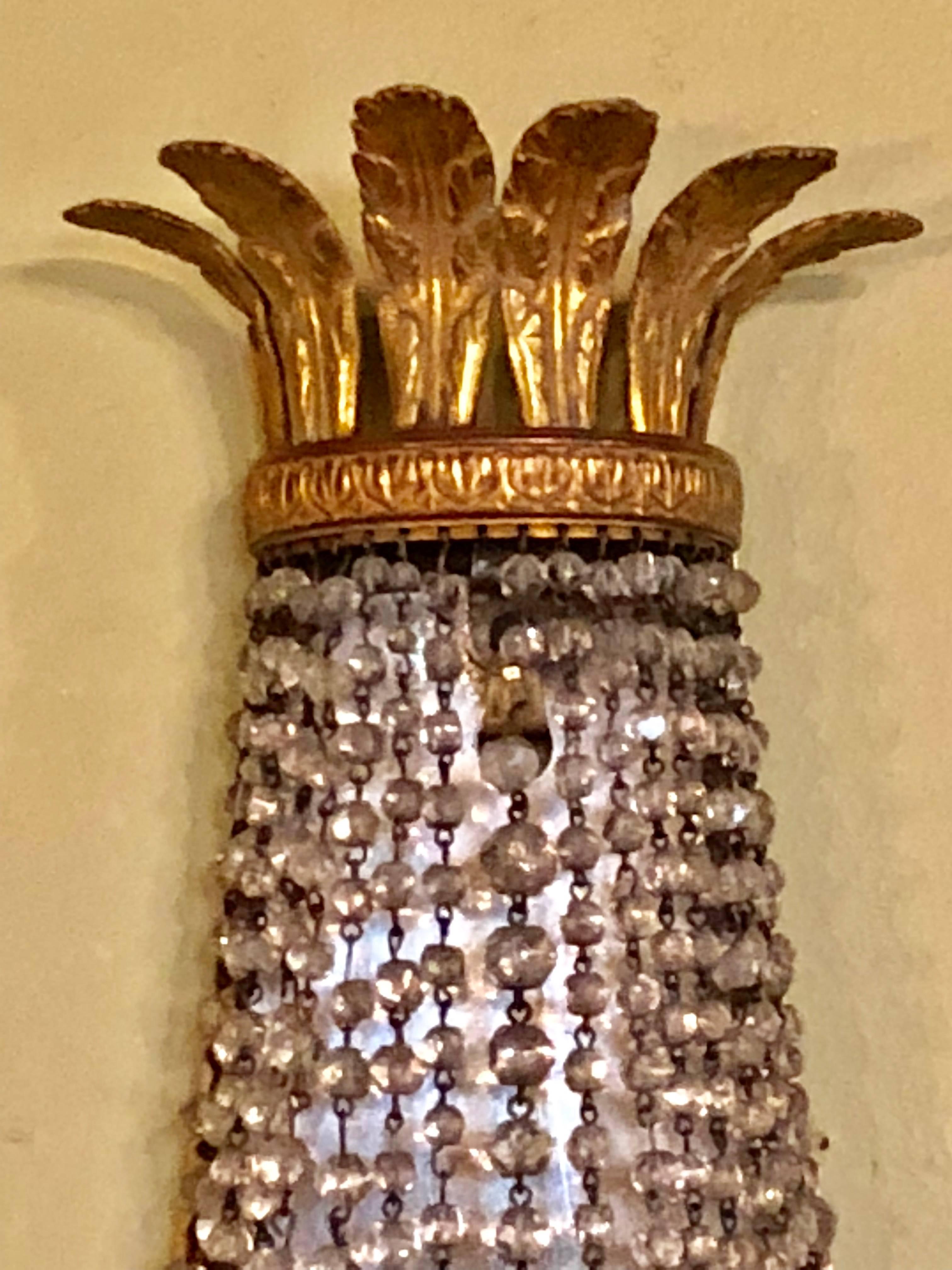Pair of French wall sconces by niermann weeks each taking three bulbs. In the neoclassical taste with hanging crystals.