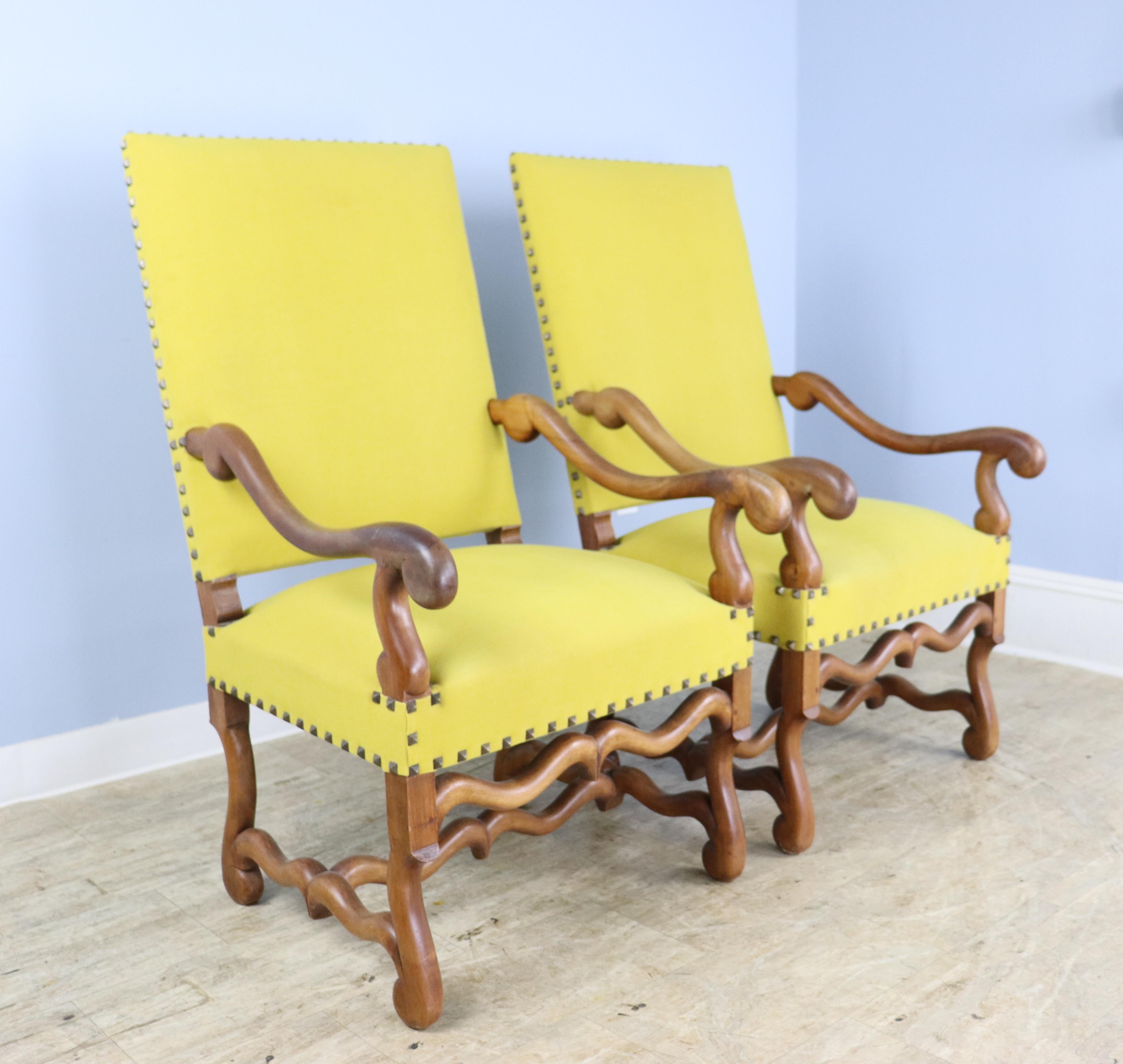 A pair of fanciful French walnut armchairs with graceful curved arms and double supports under the seats.  The new velvet upholstery is actually closer to a mustard yellow and less bright than in the photos.  Some light wear and scratches on the