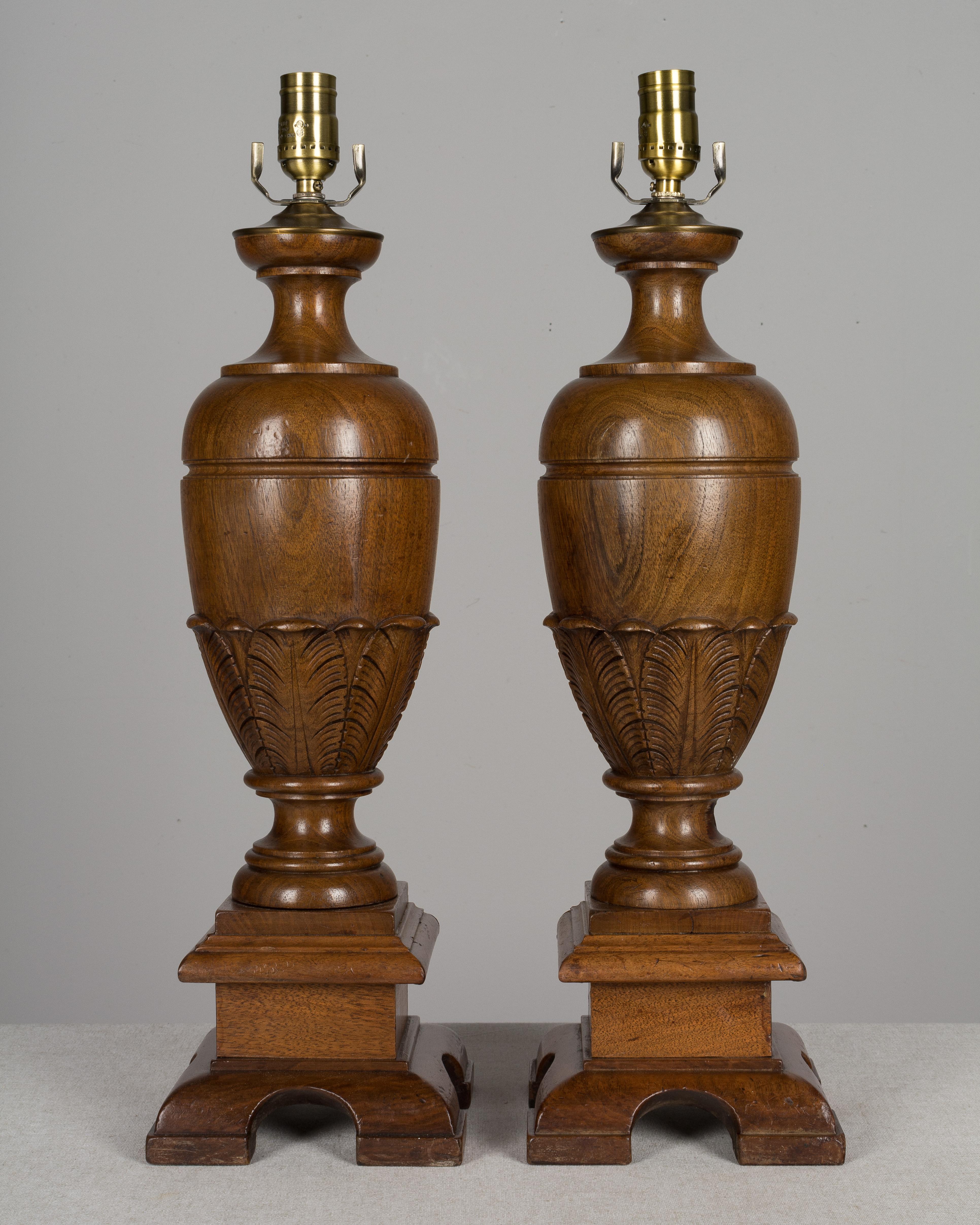 A pair of French baluster form table lamps made of solid turned walnut with carved decorative details. Made from the legs of a table. Antique brass finished caps and sockets. The shades measure 14