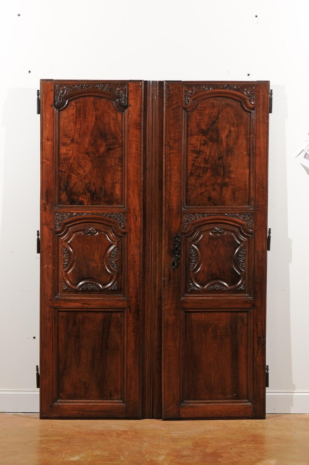 A pair of French Louis XV period hand carved walnut doors from the mid-18th century, with molded panels and foliage decor. Born in France during the reign of King Louis XV nicknamed Le Bien-Aimé (the Beloved), each of this pair of carved doors