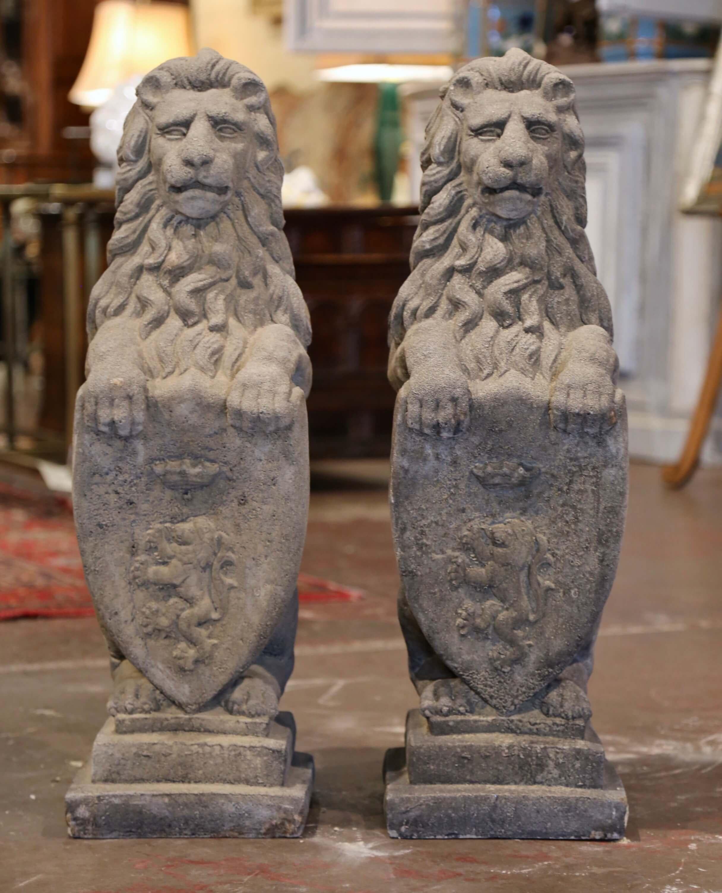 Carved of sandstone and set on integral stepped base, the tall vintage felines are shown sitting on their back legs and holding a heraldic shield with their front paws. The Westcott armorial lions have wonderful expression with long hair and thick