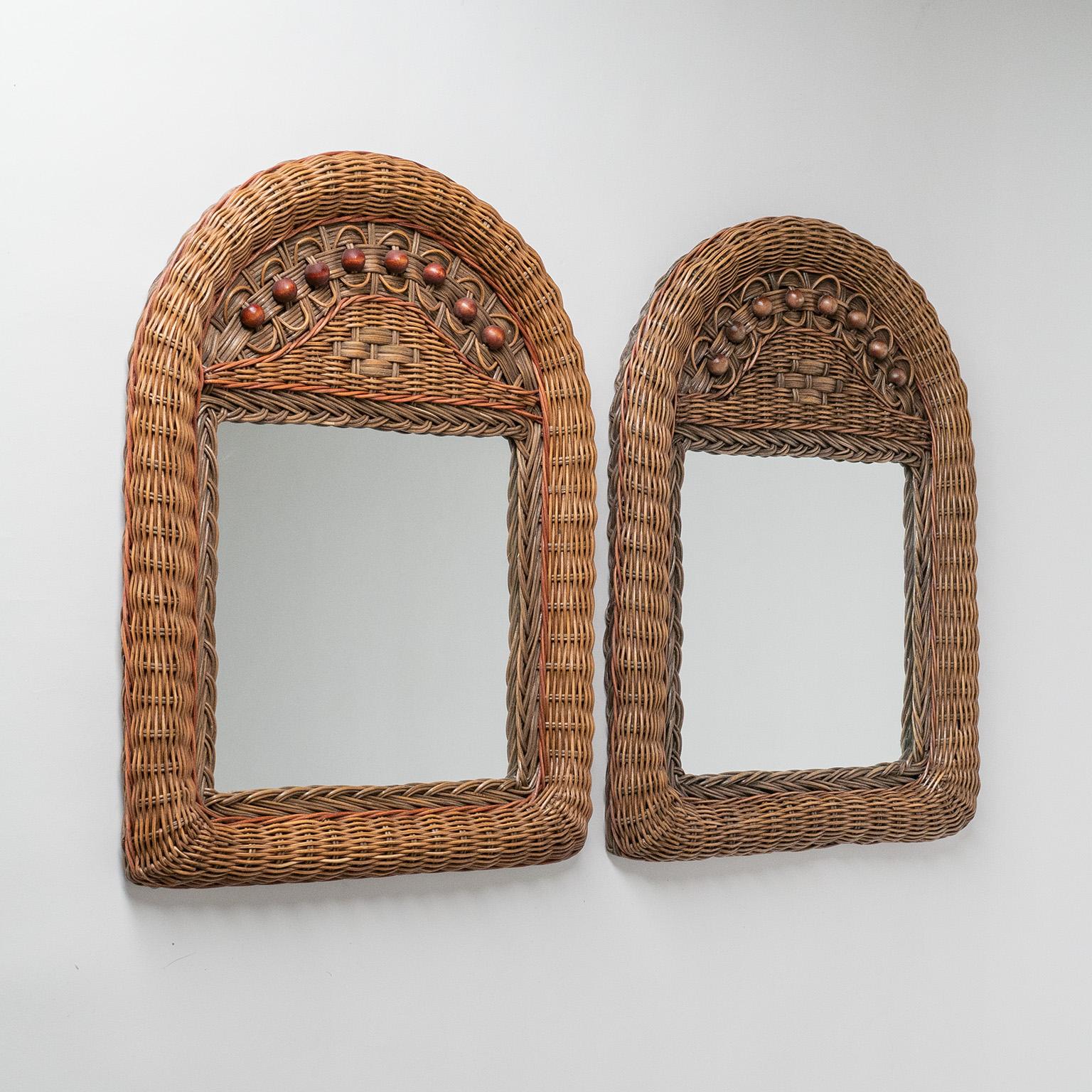 Charming pair of French wicker/rattan mirrors from the 1960-1970s. Intricate weaving techniques with color accents and wood beads. One is slightly more faded / less color.