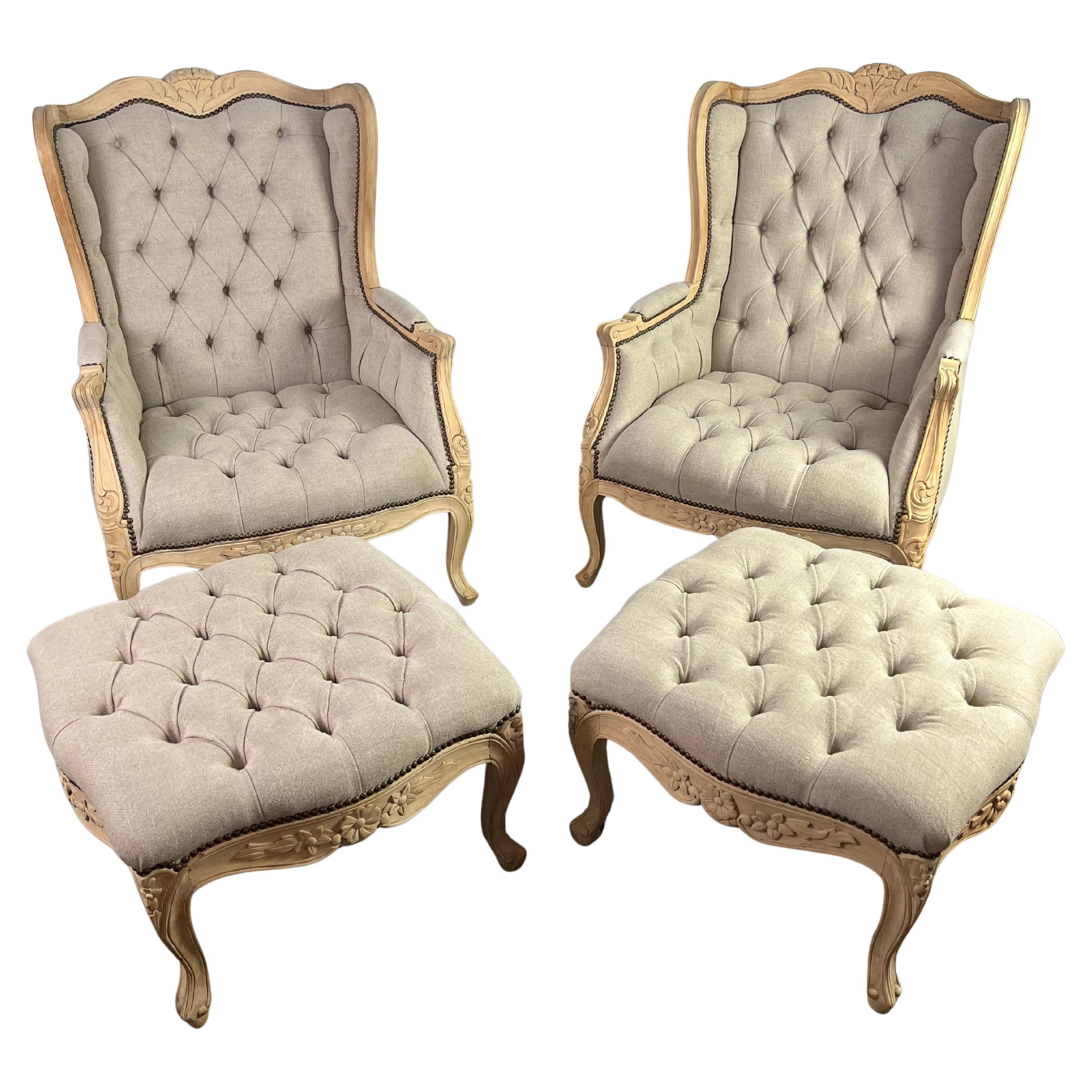 Pair of French carved bleached walnut wingback armchairs w/ matching ottomans. The chairs and ottomans stand on cabriole legs with rams head feet. The chairs are newly upholstered in a washed tufted Belgium linen with nailhead trim detail.

The