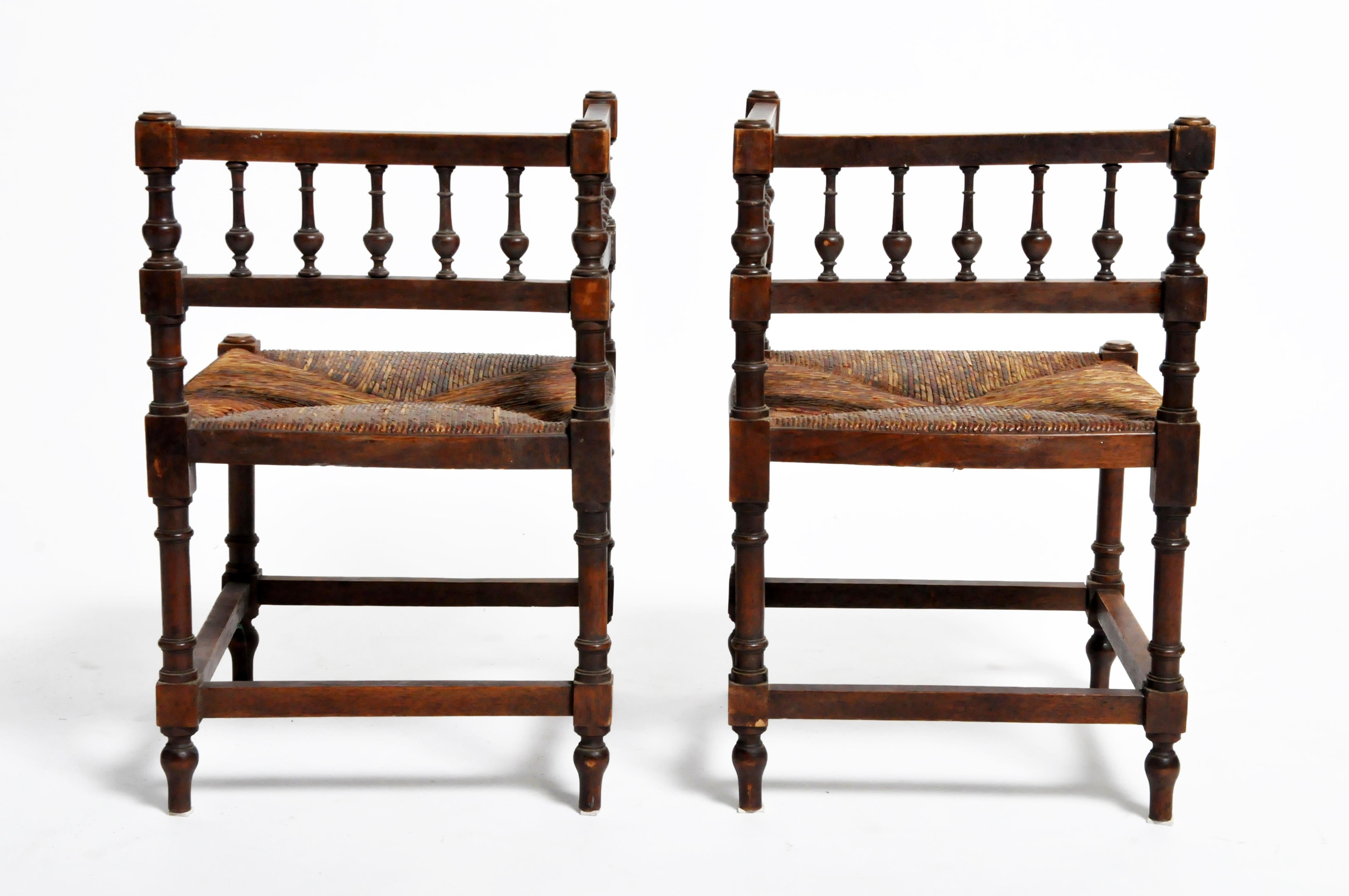 This pair of wooden corner chairs is from France and was made circa 1900. Strong and sturdy, the chairs feature comfortable rush seats and are suitable for everyday use.