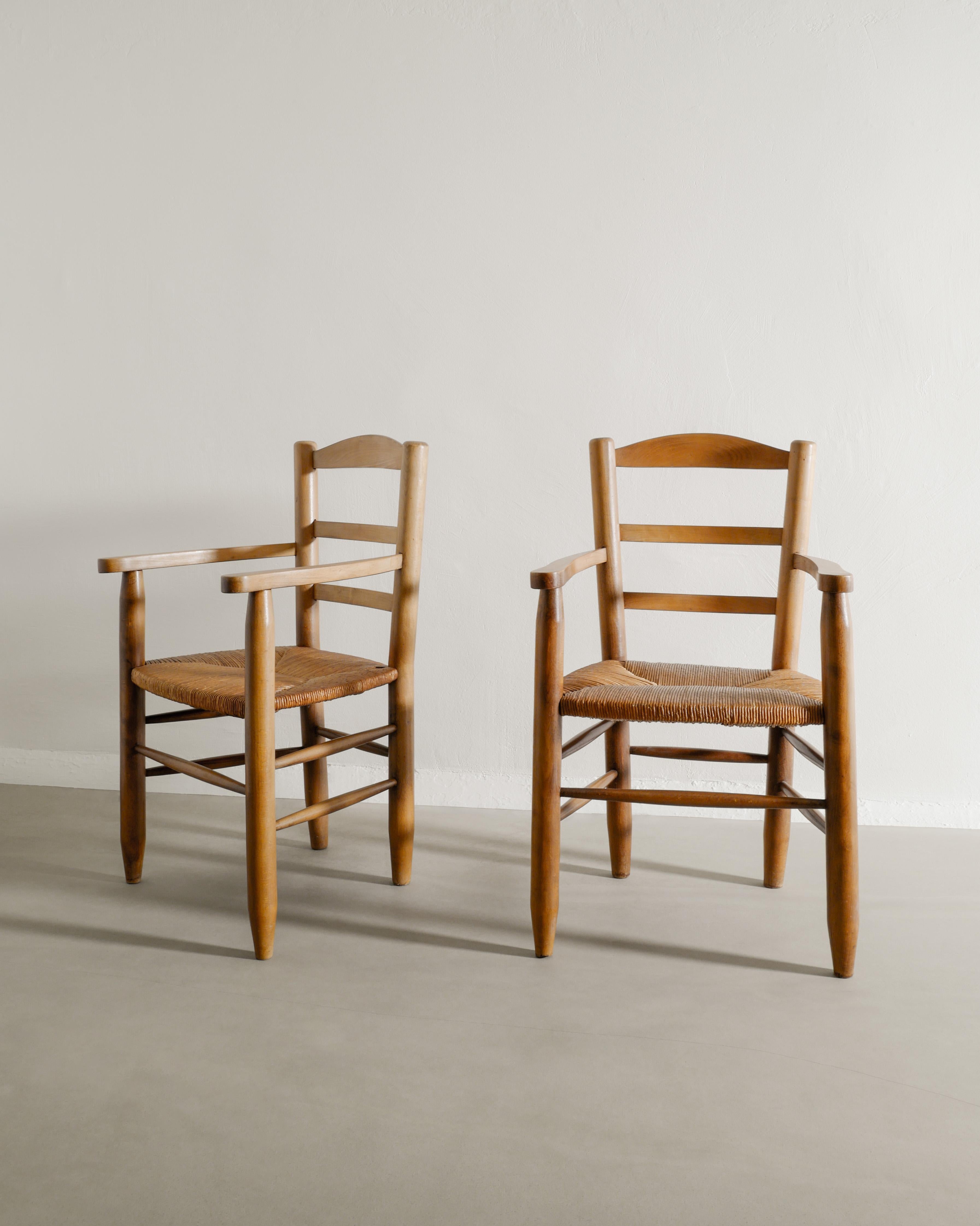 Superbe et rare paire de fauteuils en bois d'orme et assise en paille dans le style de Charlotte Perriand, produits en France dans les années 1950. En bon état d'origine et assorti. Stable et confortable. Parfaites comme chaises d'appoint, de salle