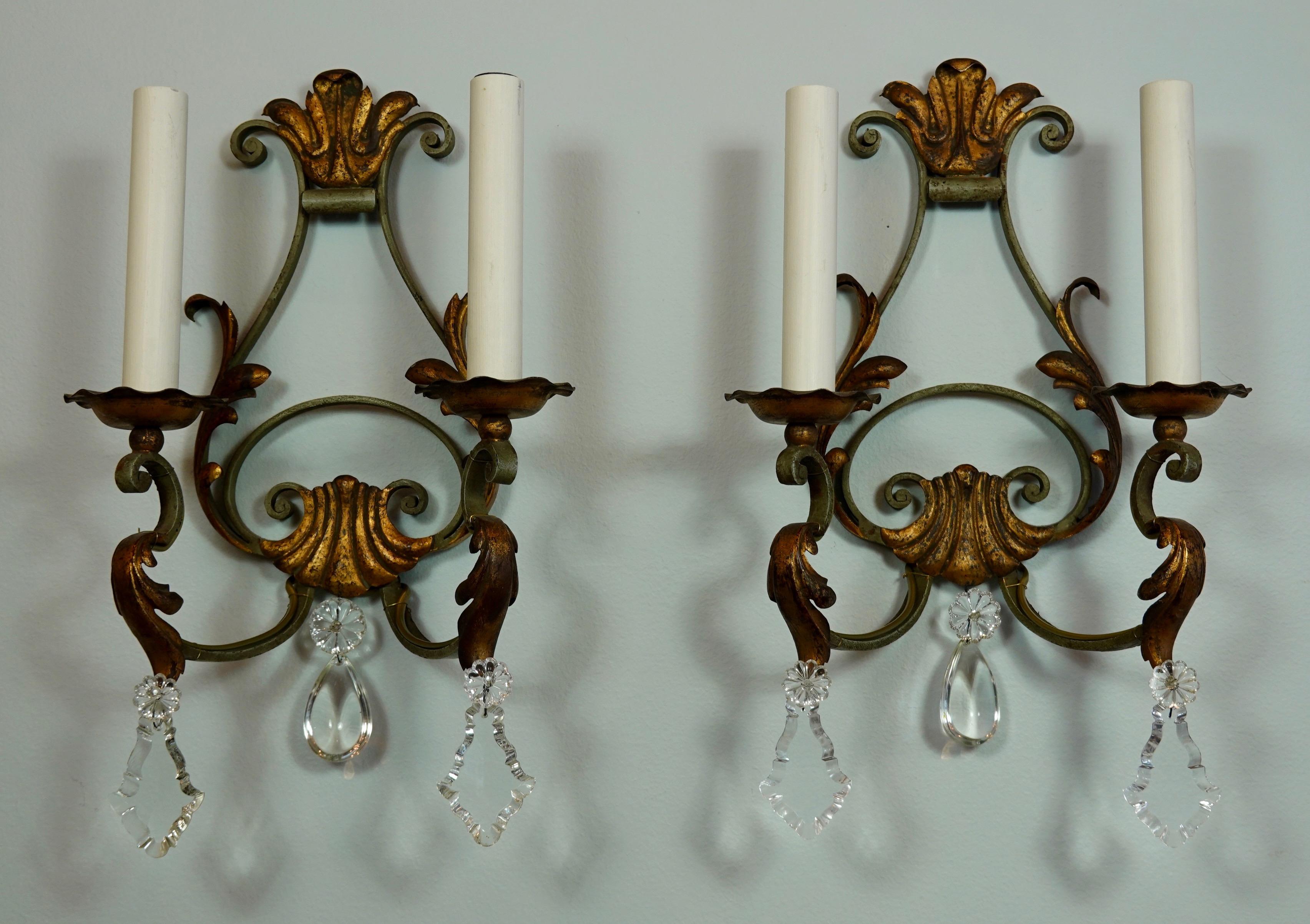 Pair of French provincial wrought iron sconces with cut crystals and gilt tole leaf details. Wrought iron is painted a light green color. To be rewired for use in the US.