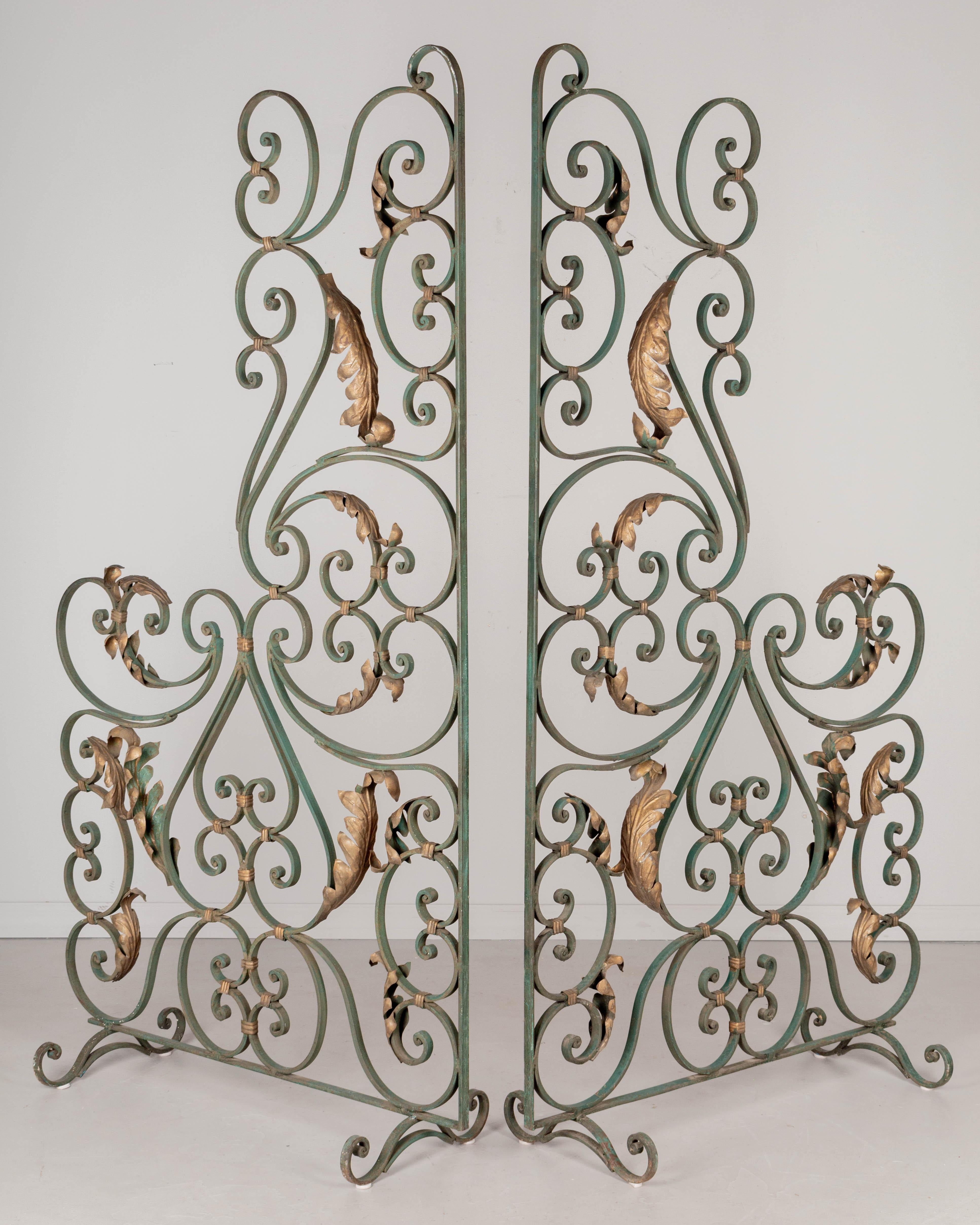 A pair of French Art Deco wrought iron screens or room dividers with original green painted patina and gilt tôle leaves. Heavy, free-standing frames with good quality iron work. Circa 1930-1950. 
Each panel: 75